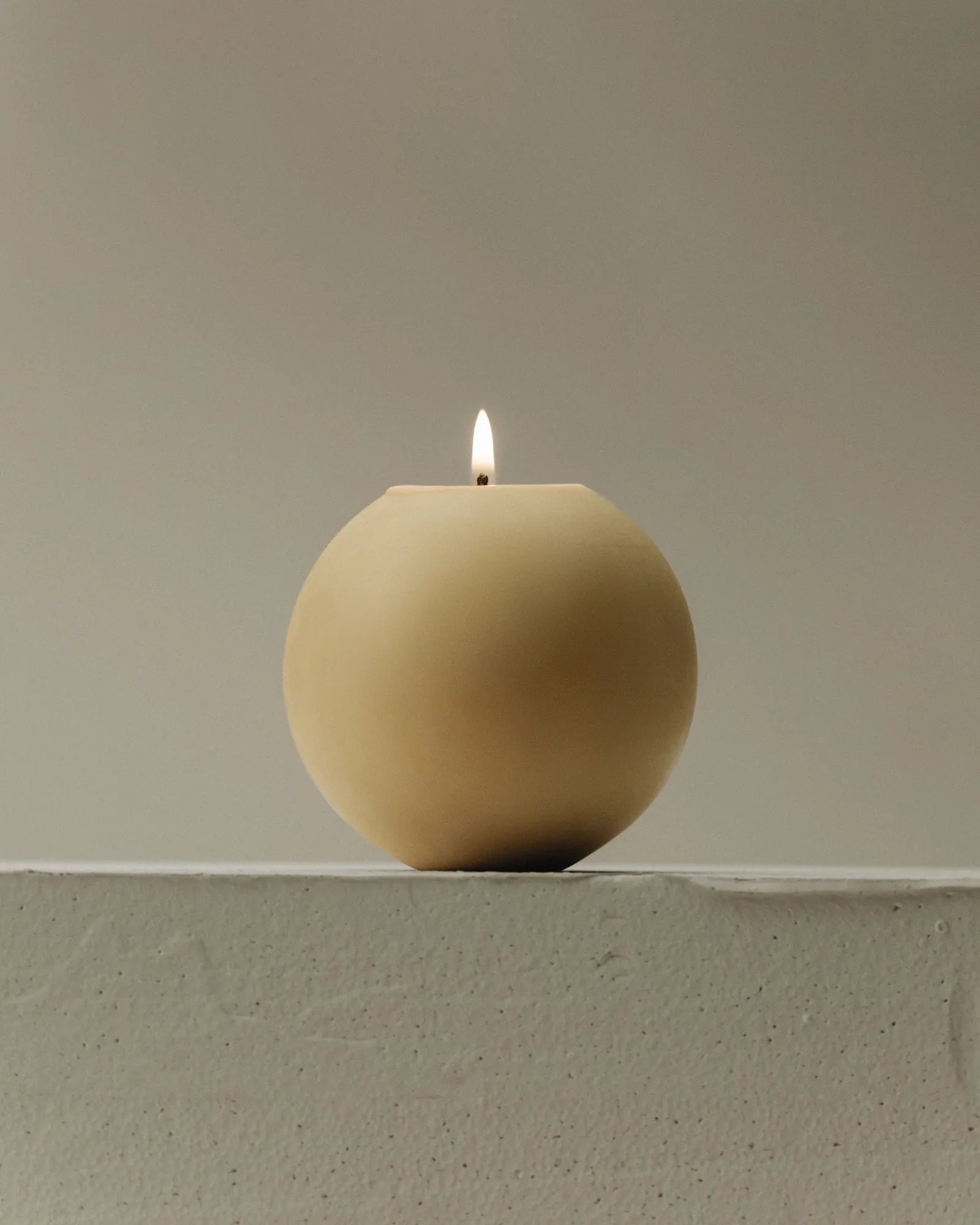 Round sculptural soy candle lit on a concrete ledge — LAWA Candles Los Angeles