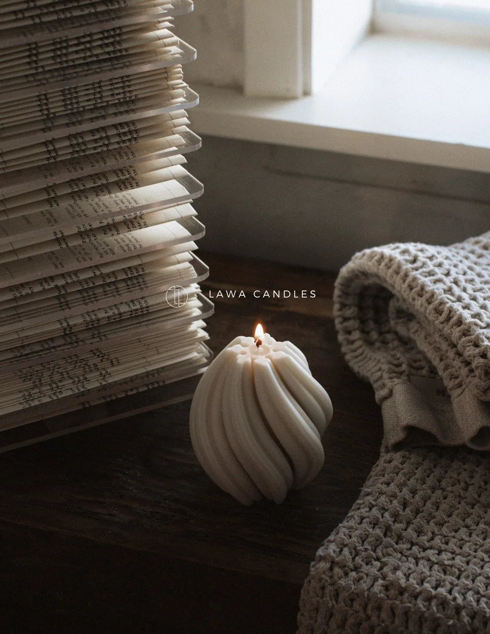 Handmade sculptural soy candle lit beside an open book and knit throw — LAWA Candles Los Angeles