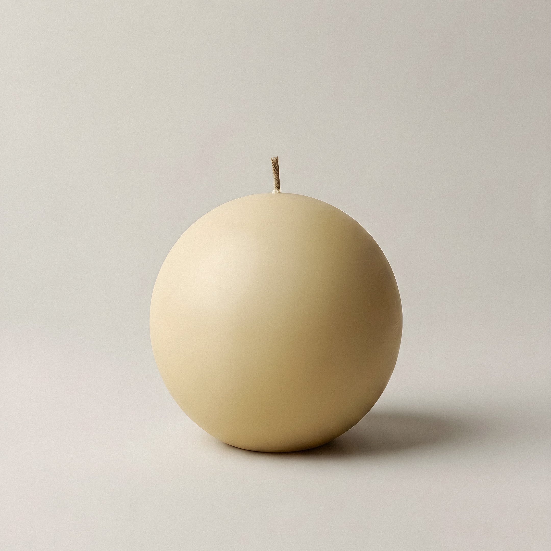 Handmade unscented sphere candle detail showing smooth soy wax texture and sculptural form on minimalist surface