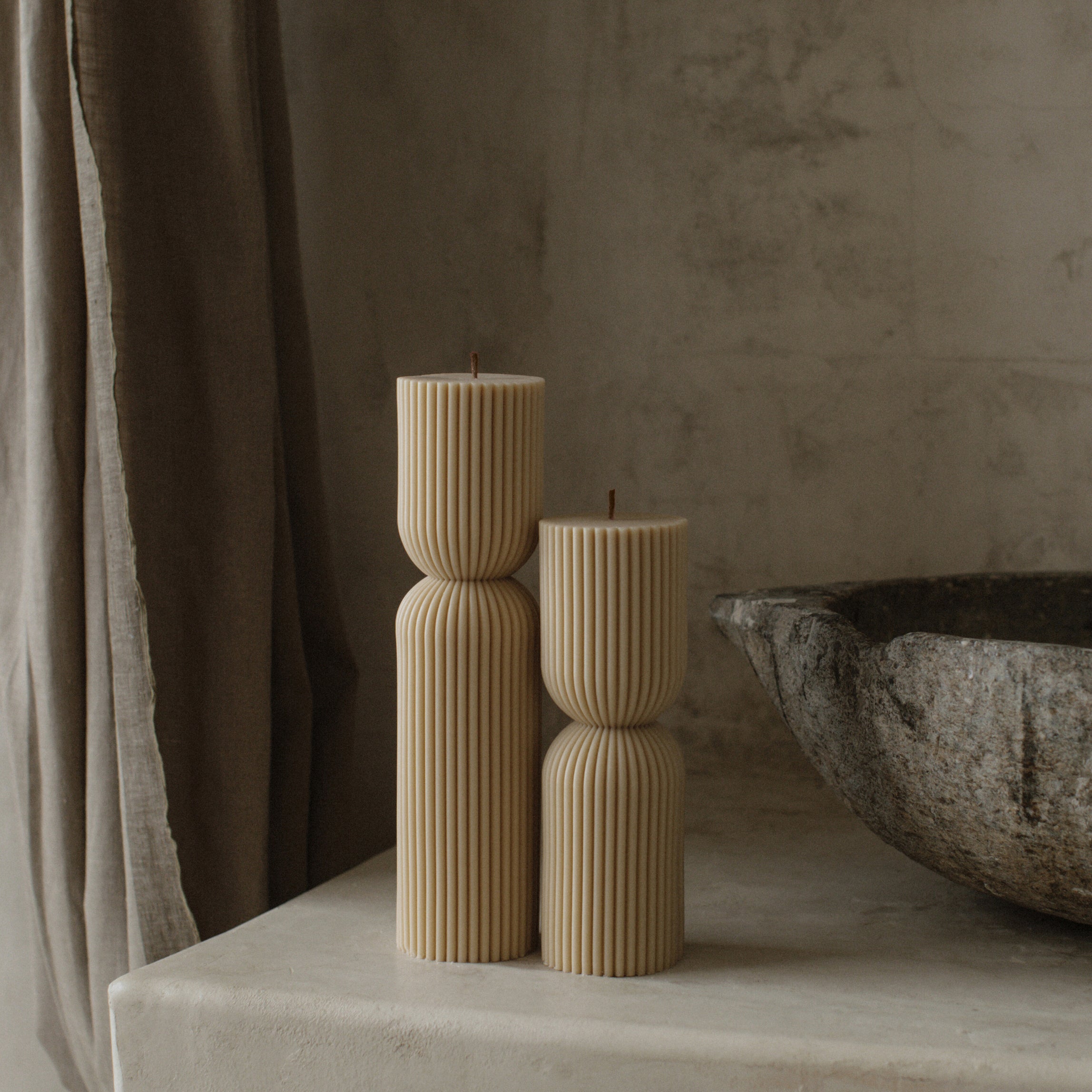 Close-up detail of handmade hourglass sculptural candle showing smooth soy wax texture and cotton wick
