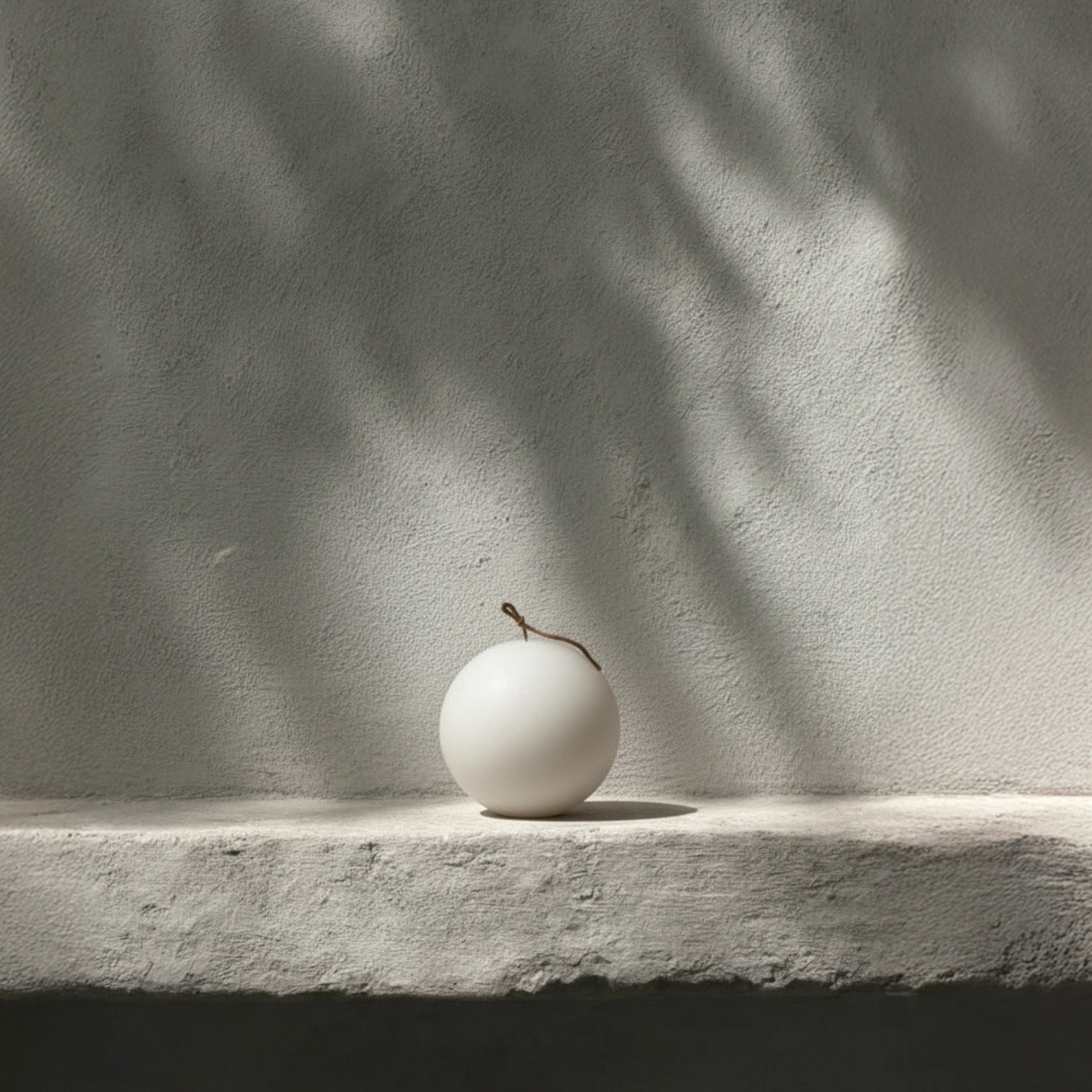 Handmade sphere sculptural candle detail showing smooth soy wax texture in minimalist Los Angeles home setting