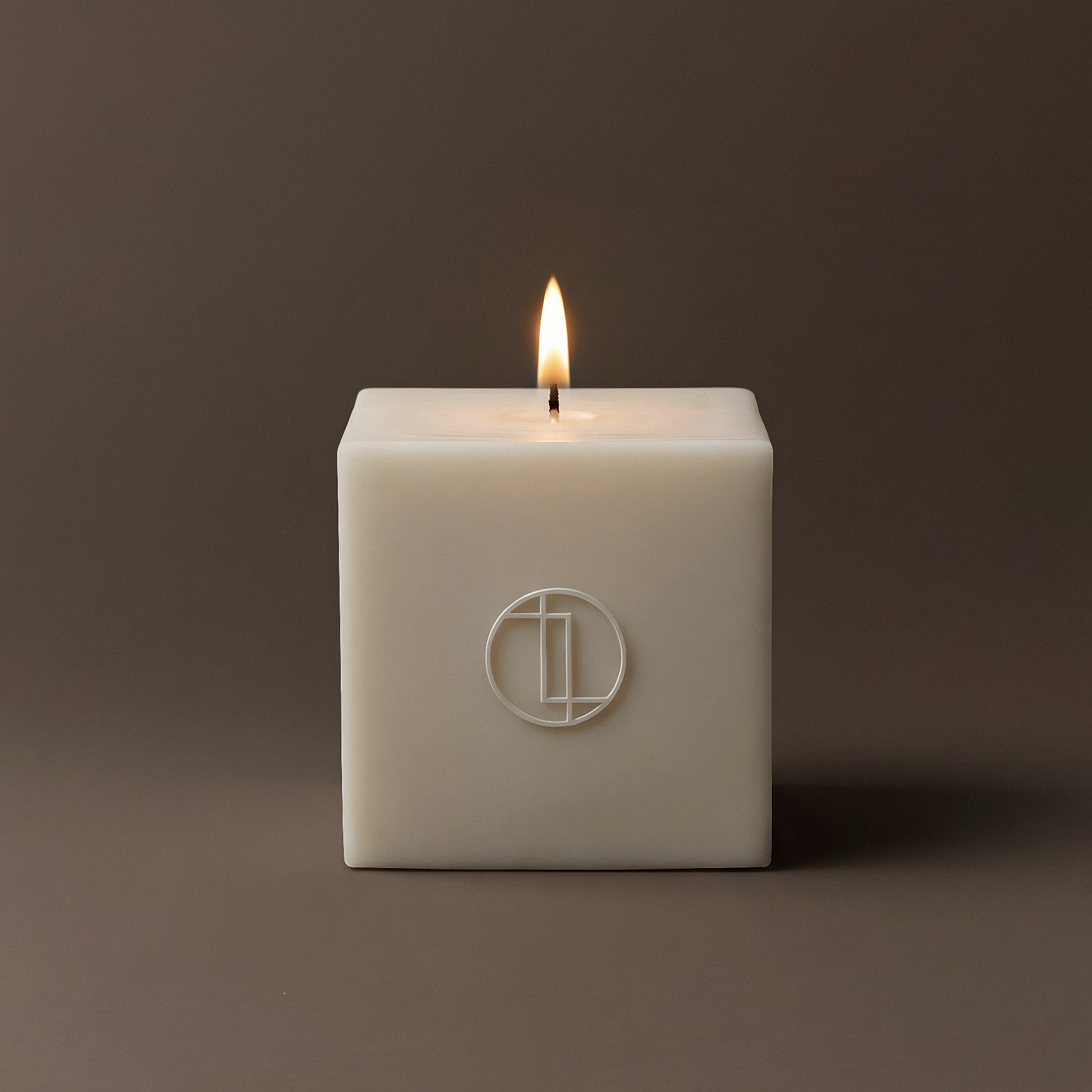 Square cream candle with a logo on a dark brown background
