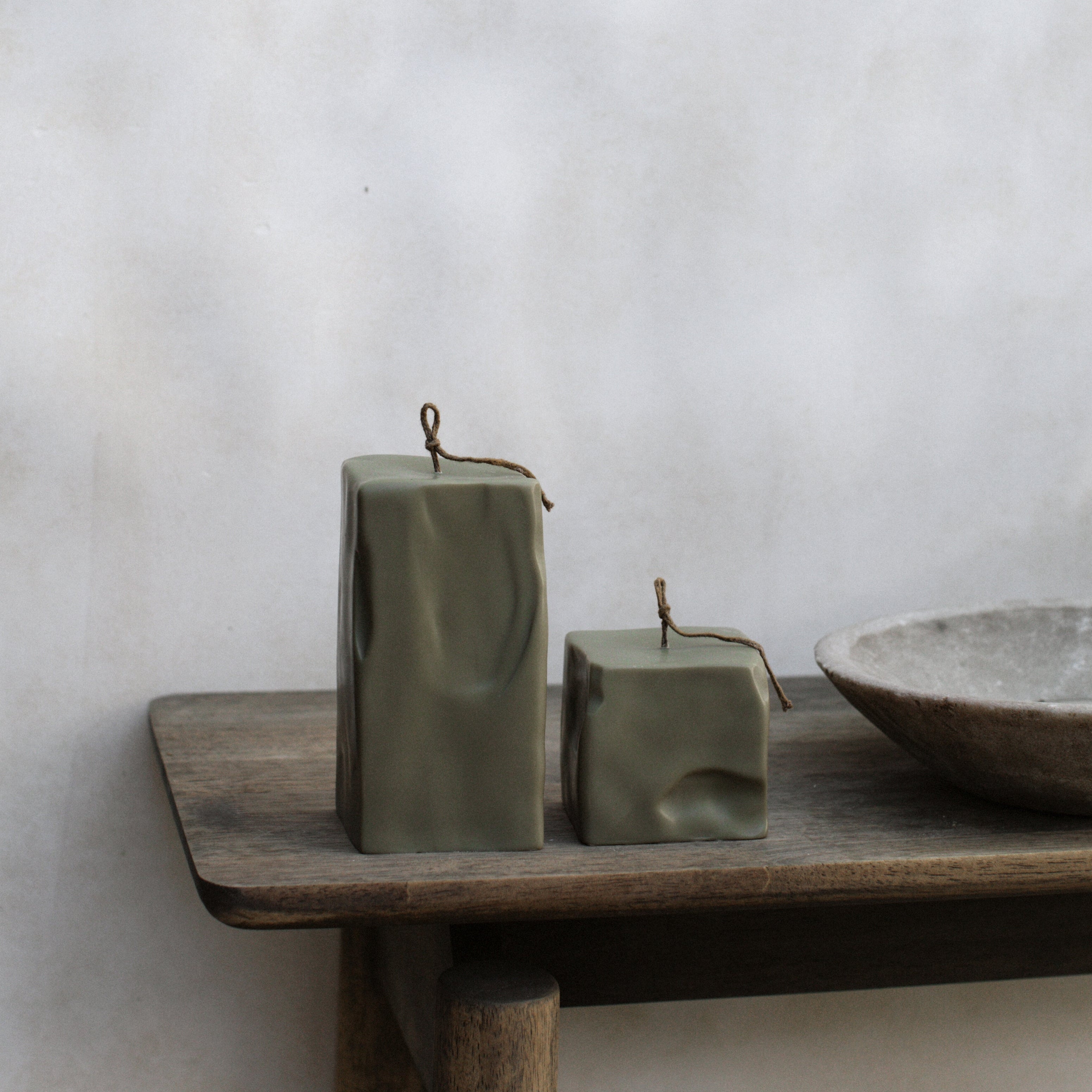 LAWA earthy green raw block candle set of 2 on a wooden shelf against a plain wall.