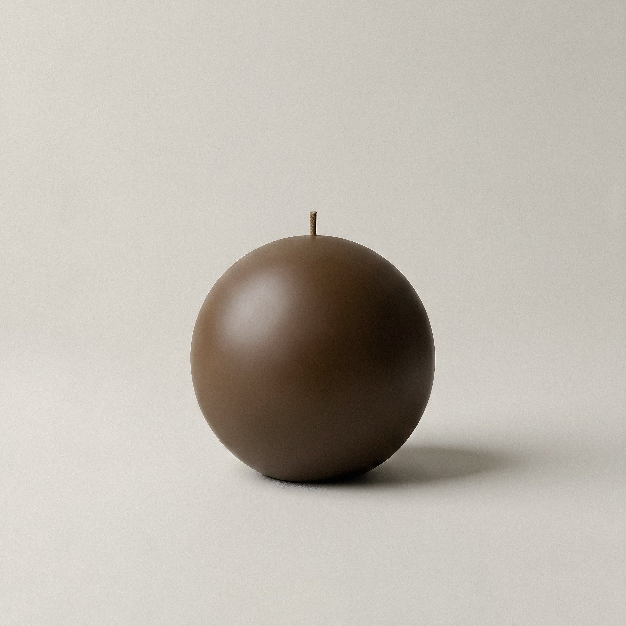 Handmade sphere sculptural candle detail showing smooth soy wax texture in minimalist Los Angeles home setting
