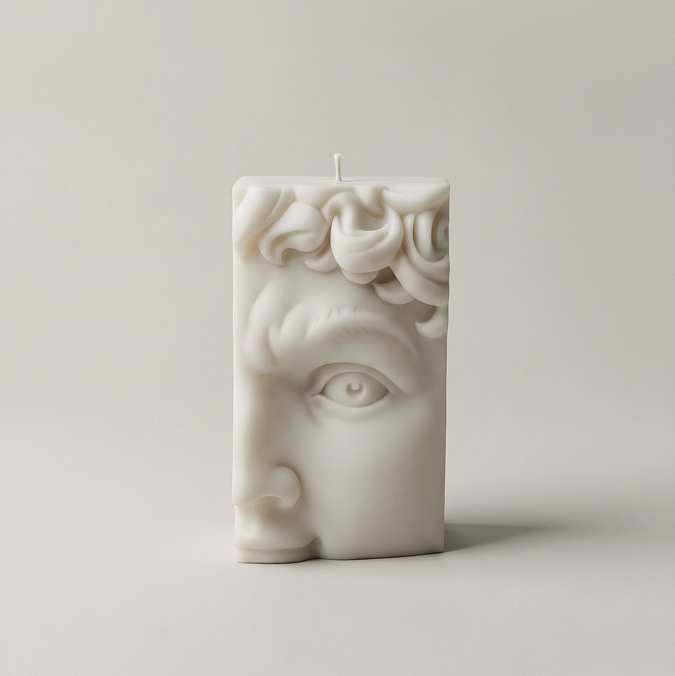Close-up detail of handmade David's Half Face sculptural candle showing textured soy wax surface and cotton wick