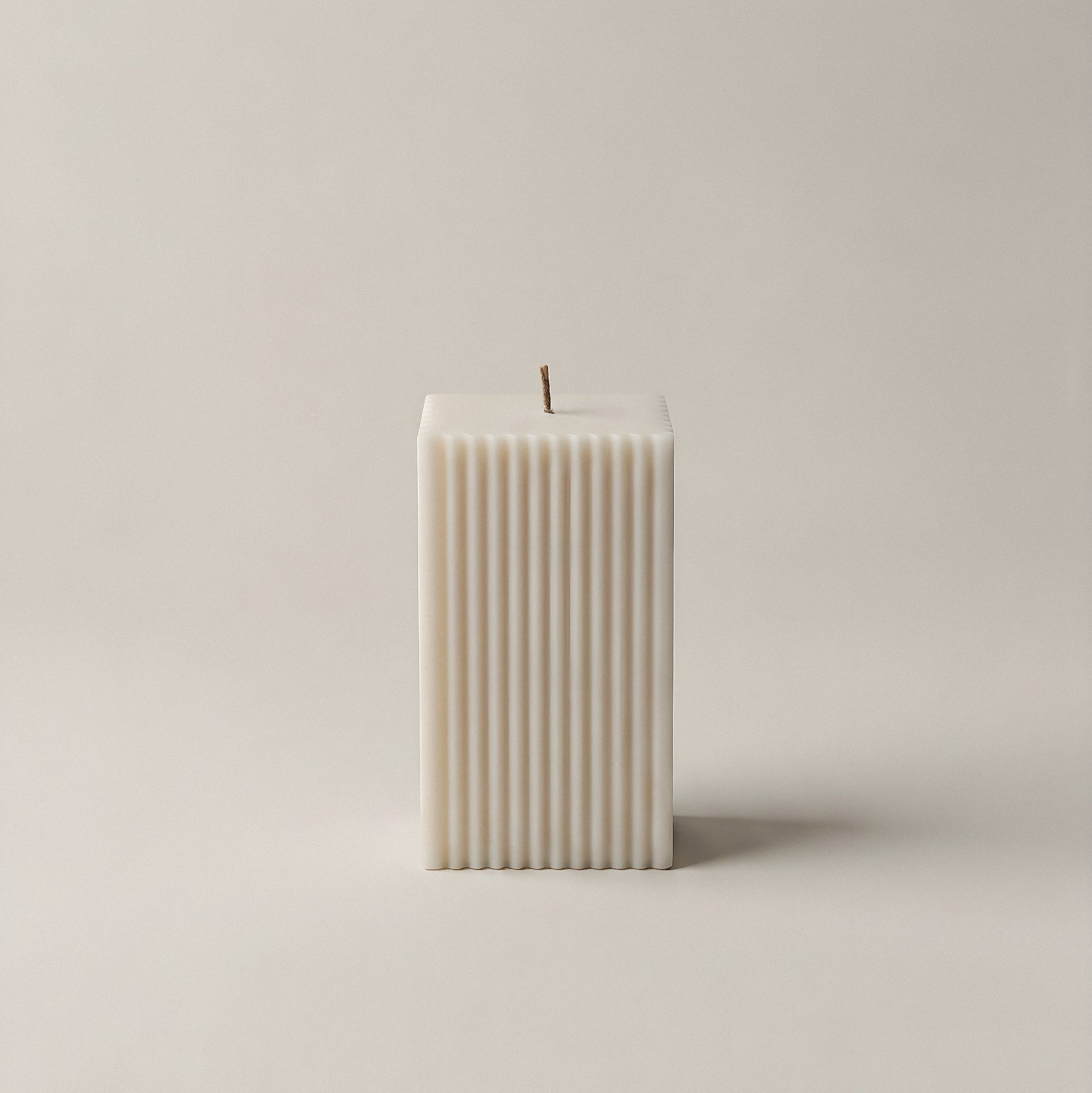 Square ribbed sculptural candle in white soy wax handmade in Los Angeles against neutral background