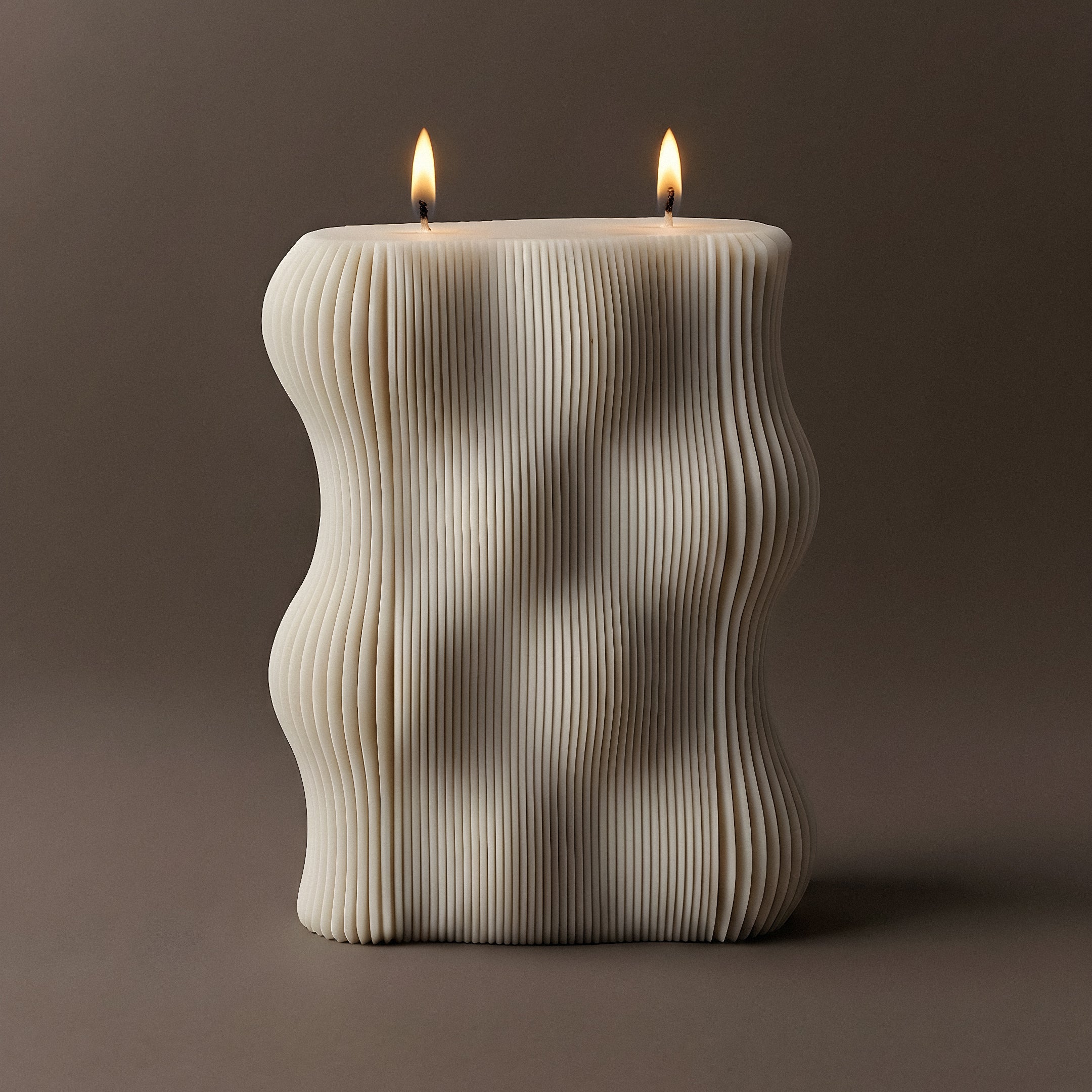 Handmade wavy sculptural candle detail showing smooth soy wax curves and organic flowing form on neutral surface