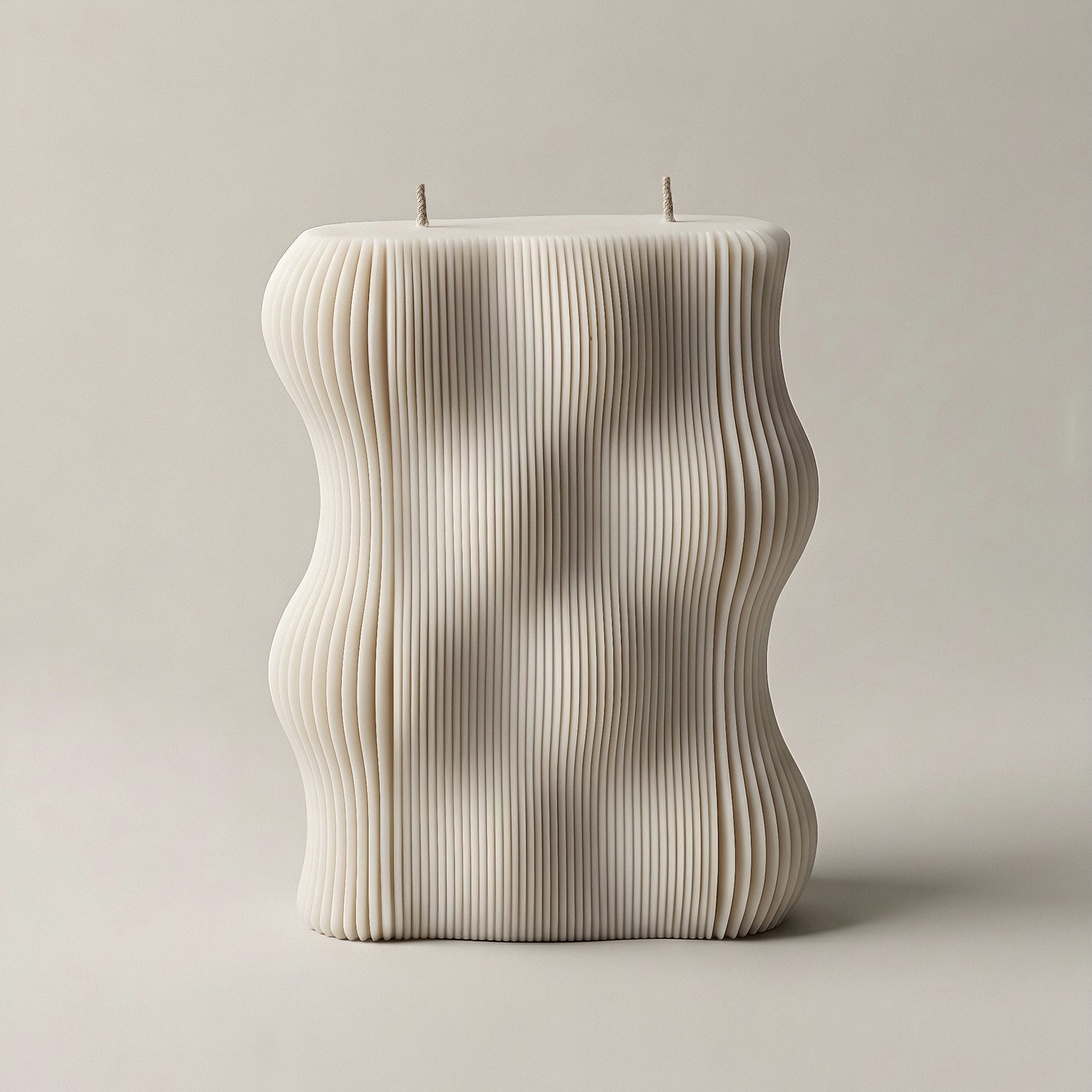 Handmade wavy sculptural candle detail showing smooth soy wax curves and organic flowing form on neutral surface