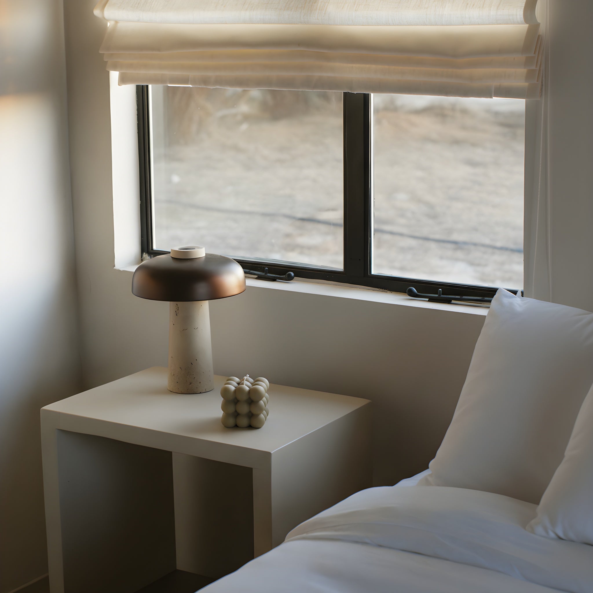 Earthy olive beige bubble candle by LAWA with stacked soy wax bubbles on a nightstand, lamp, and decorative items near a window.