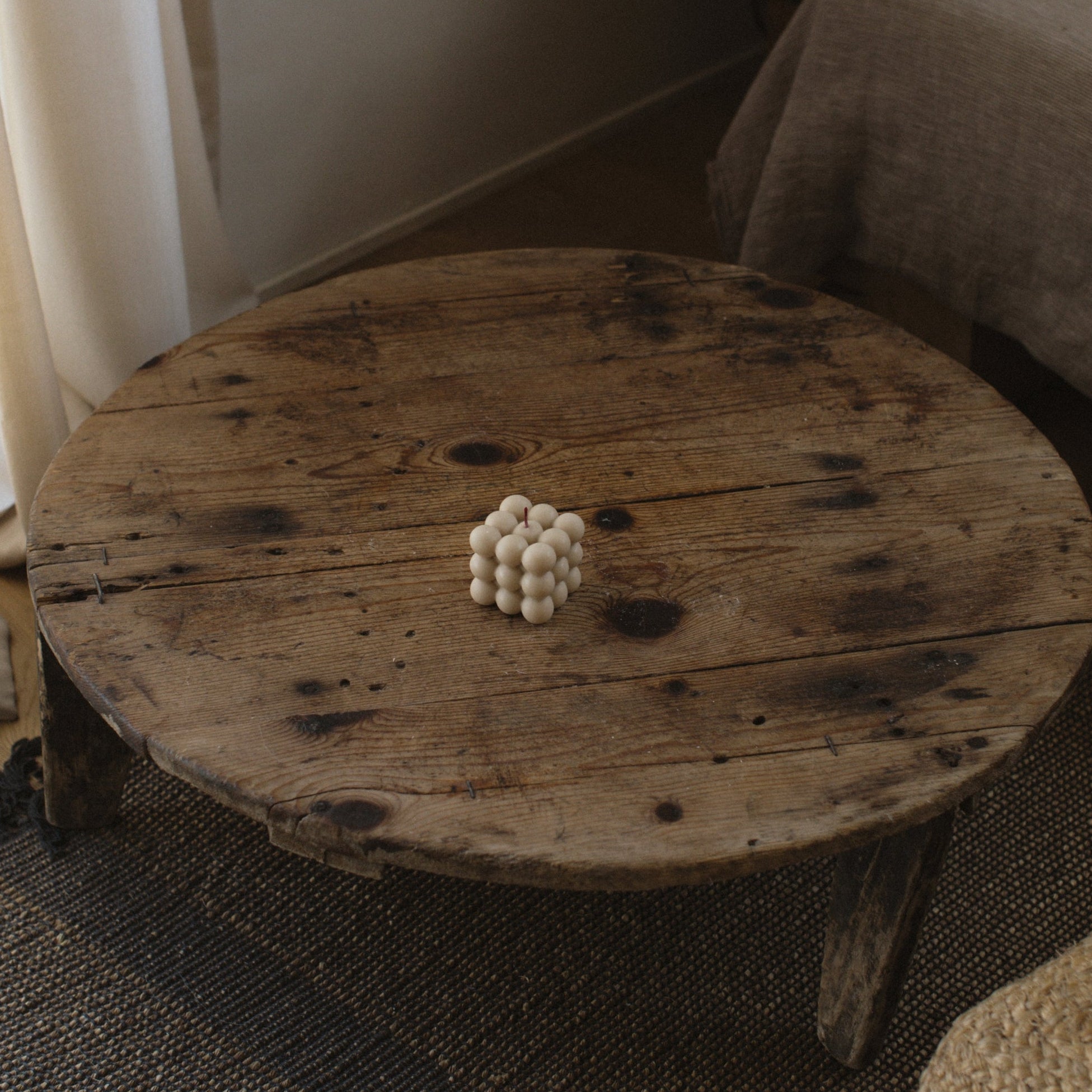 Moon gray bubble pillar candle by LAWA, minimalist sculptural decor piece on Round wooden table with a textured rug
