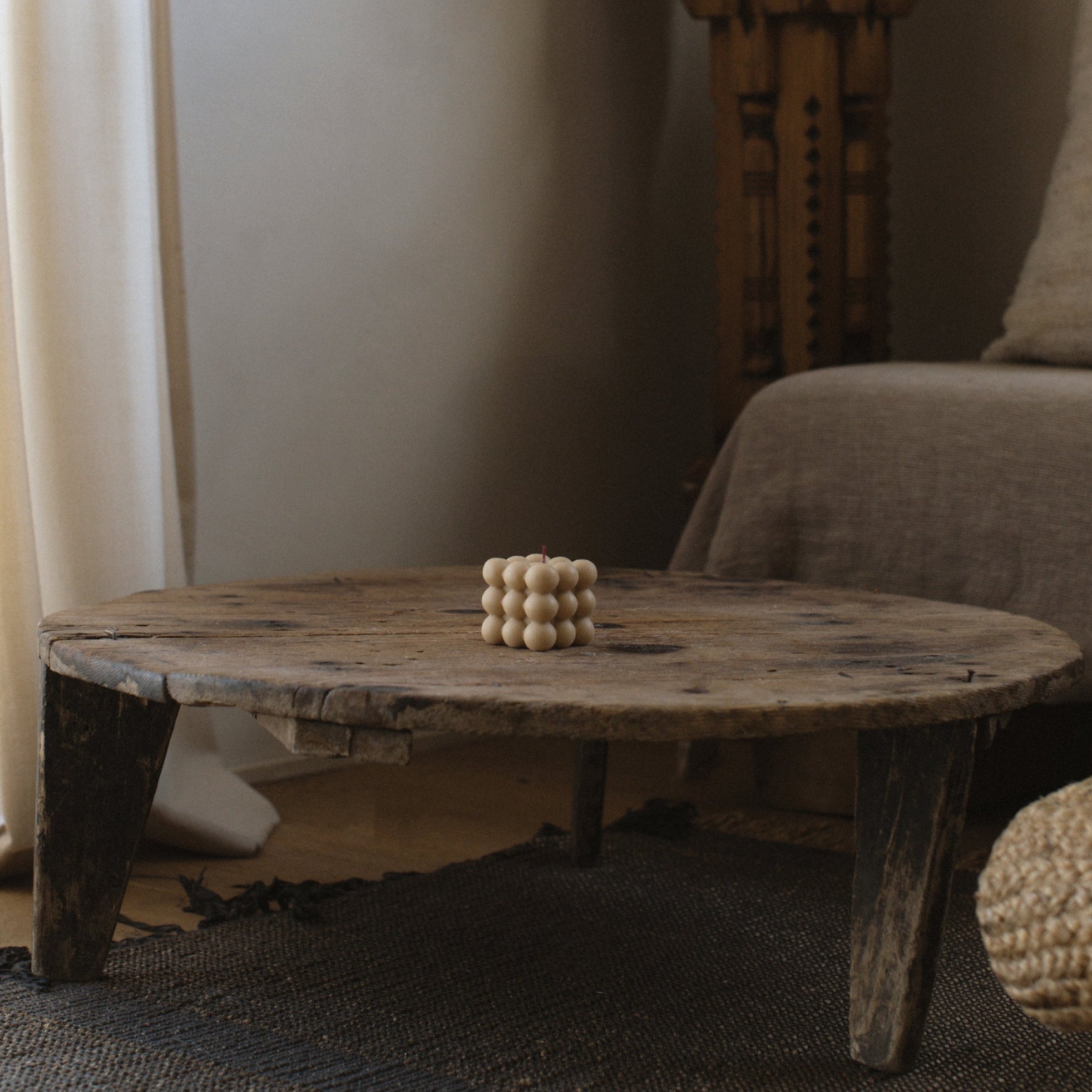 Neutral sandstone bubble candle by LAWA featuring stacked rounded soy wax forms on Wooden coffee table  in a living room setting