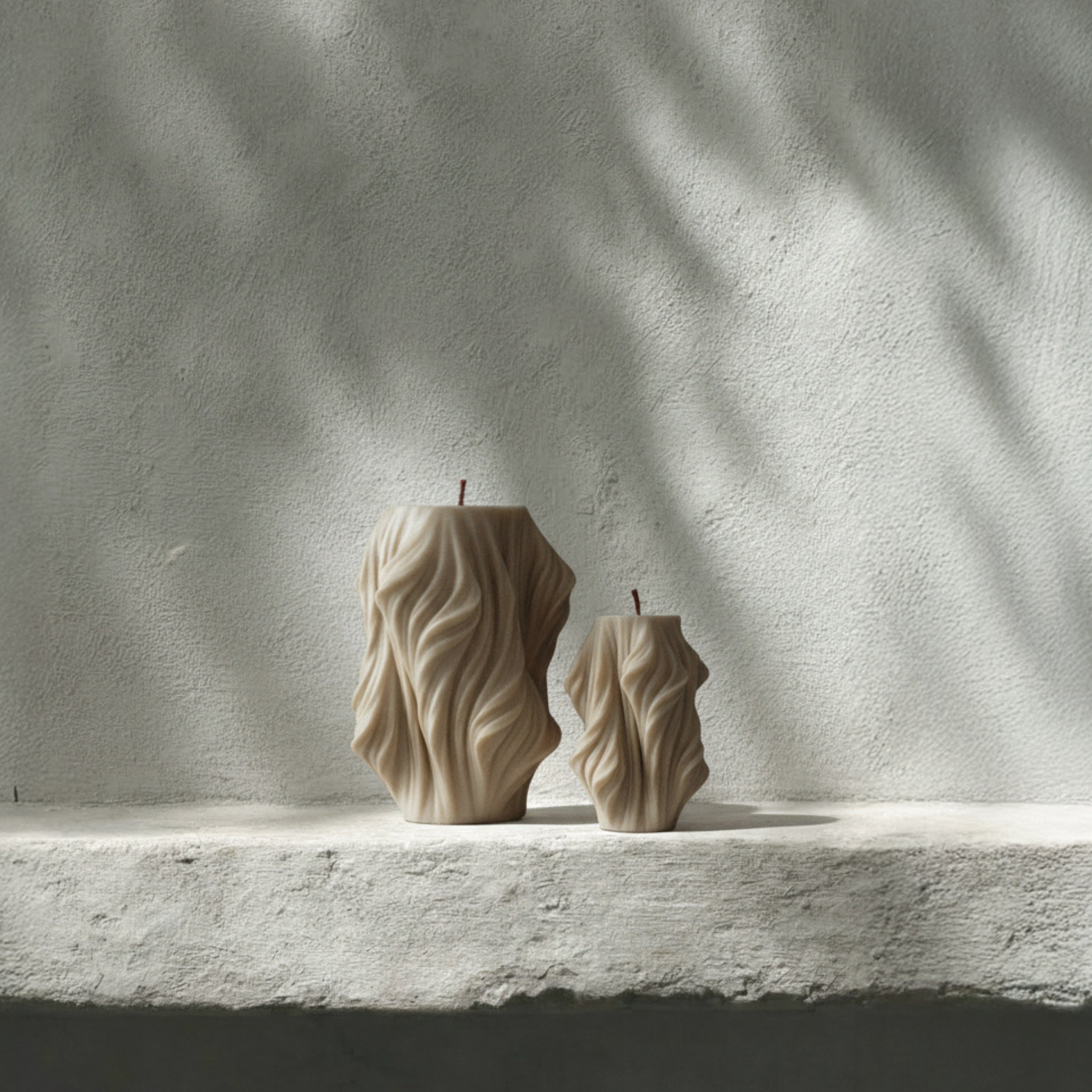 Moon Gray cascading pillar candle duo featuring modern geometric contours by LAWA on a stone surface with a textured wall background.