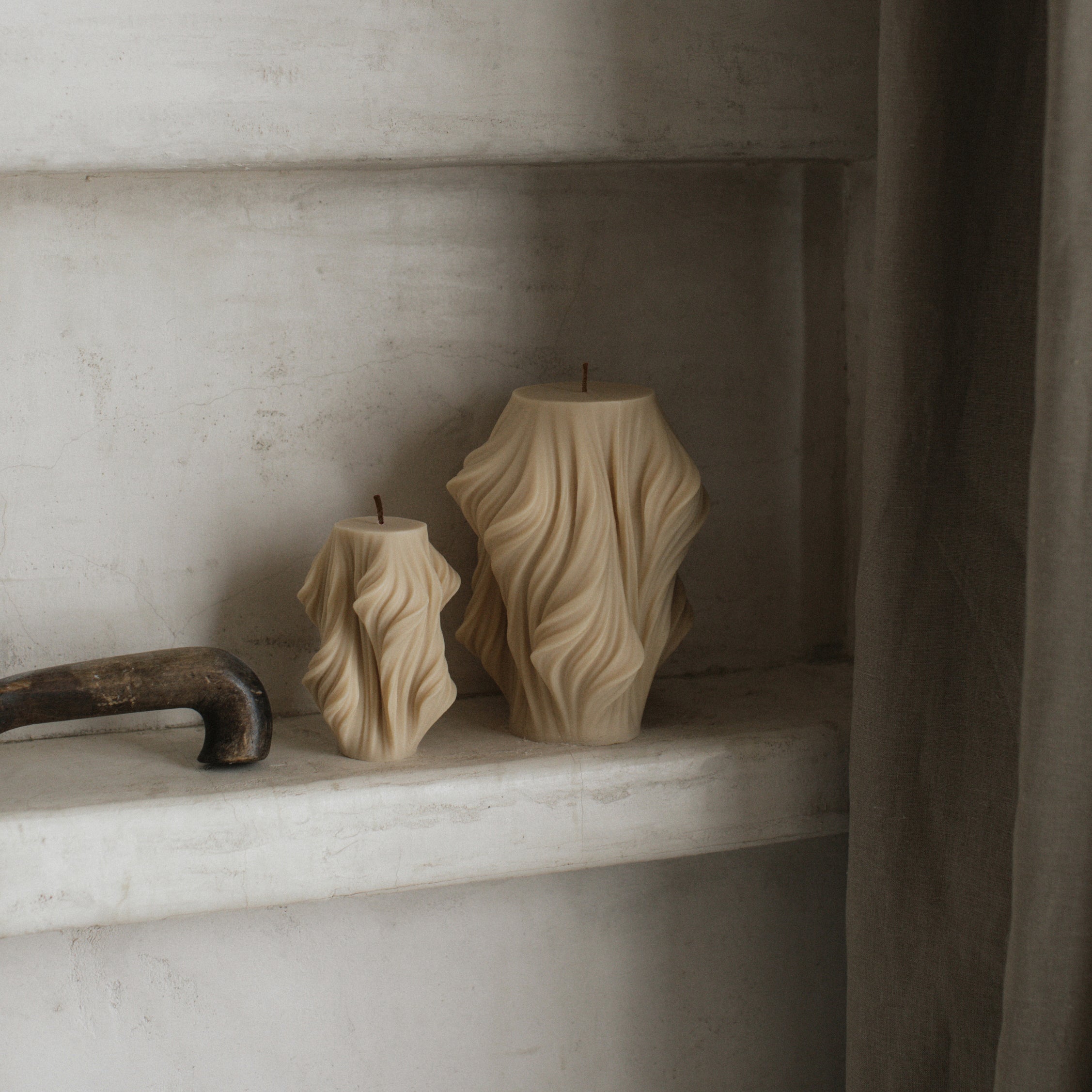 Sandstone cascading set of two pillar candles on a shelf in a minimalistic setting