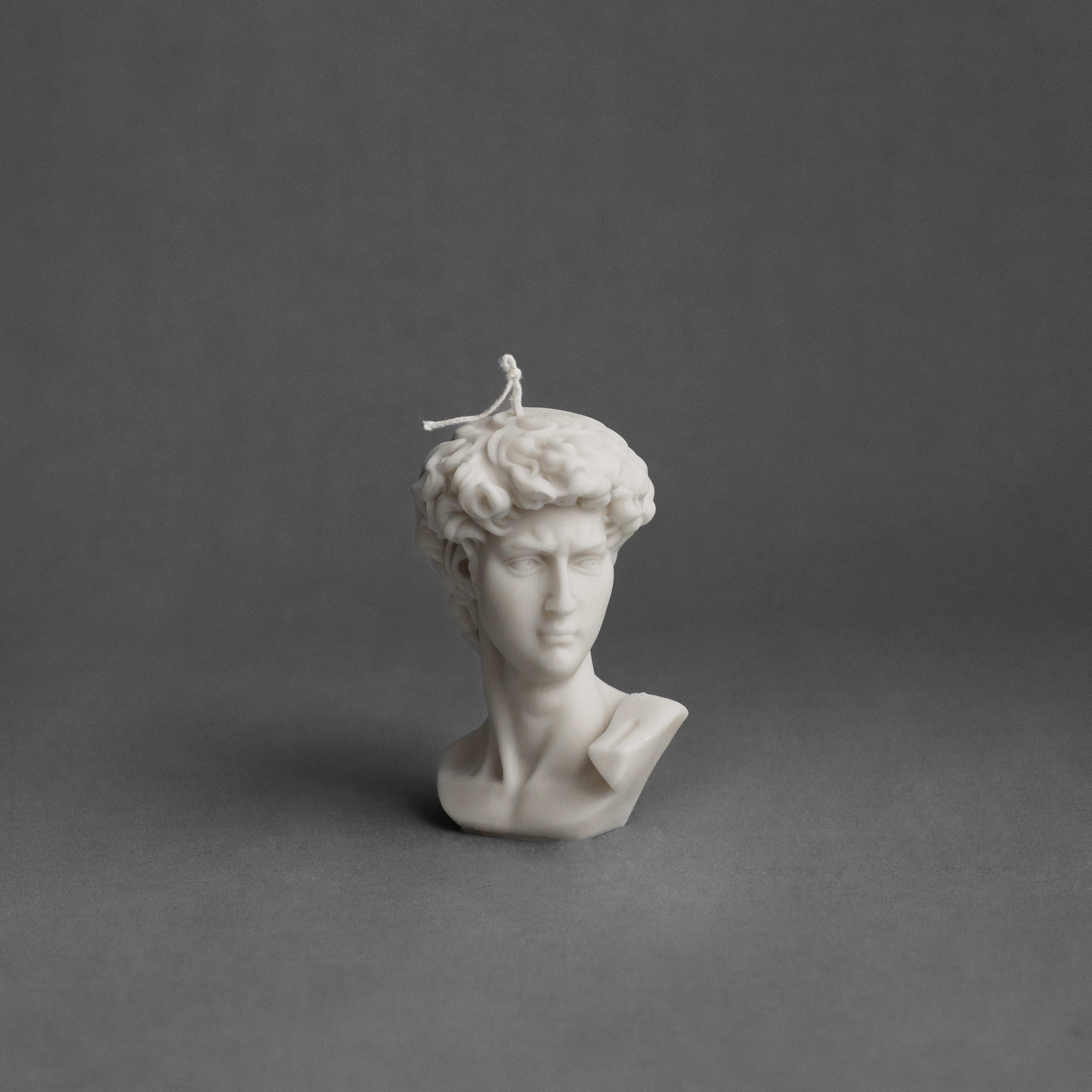 White sculptural bust candle on a gray background