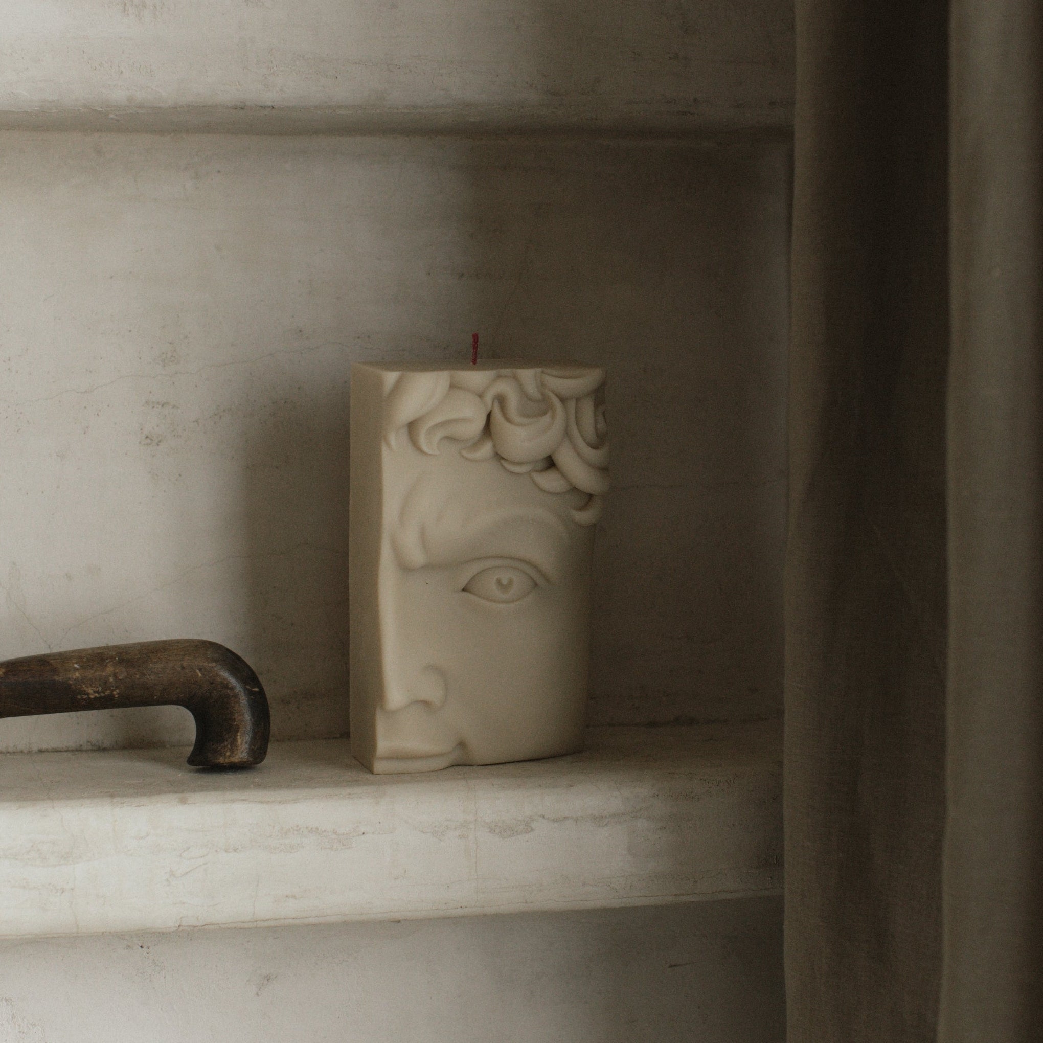 David half face soy wax pillar candle  on a shelf with a neutral background