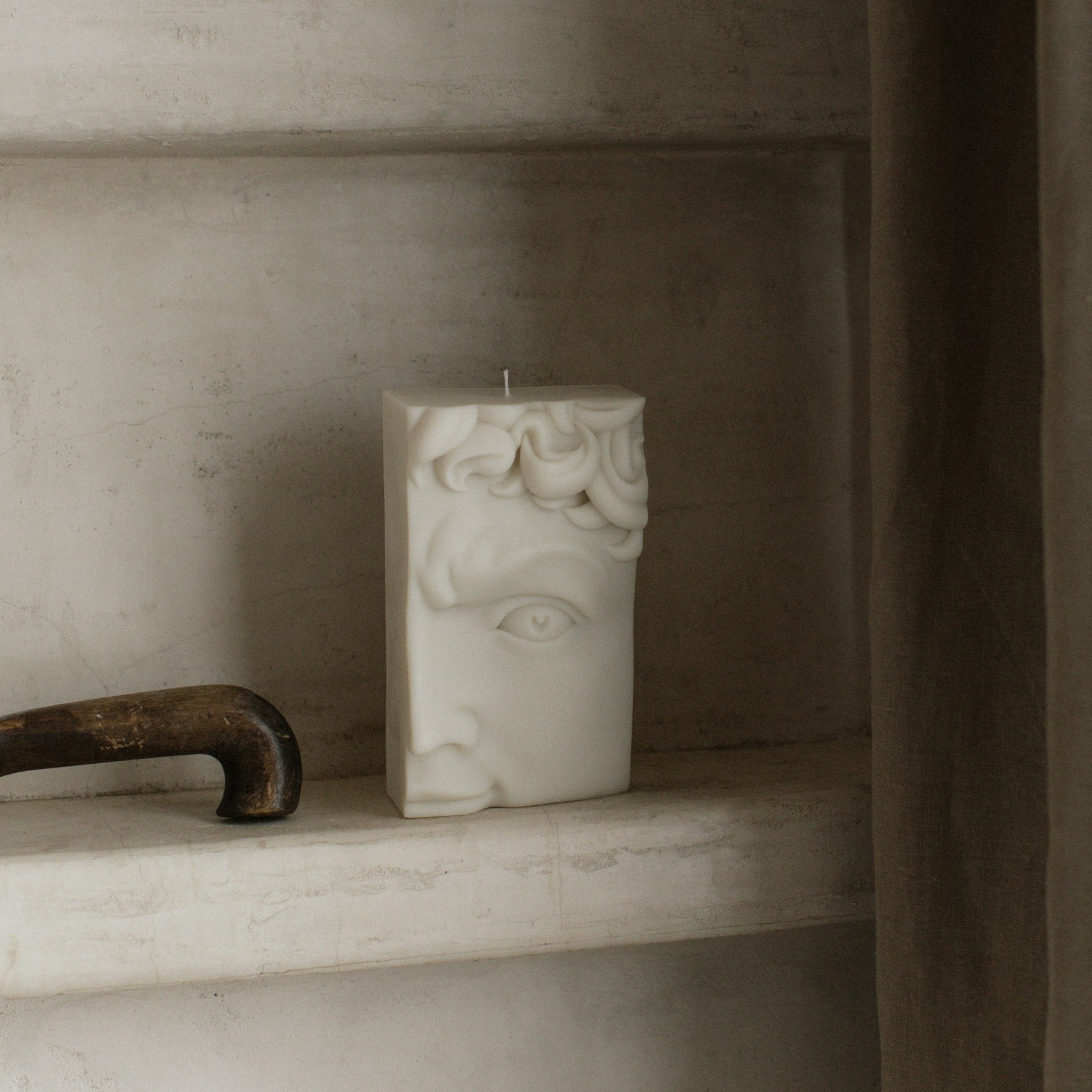 Handmade sculptural candle featuring half face design in soy wax on minimalist table setting in Los Angeles studio