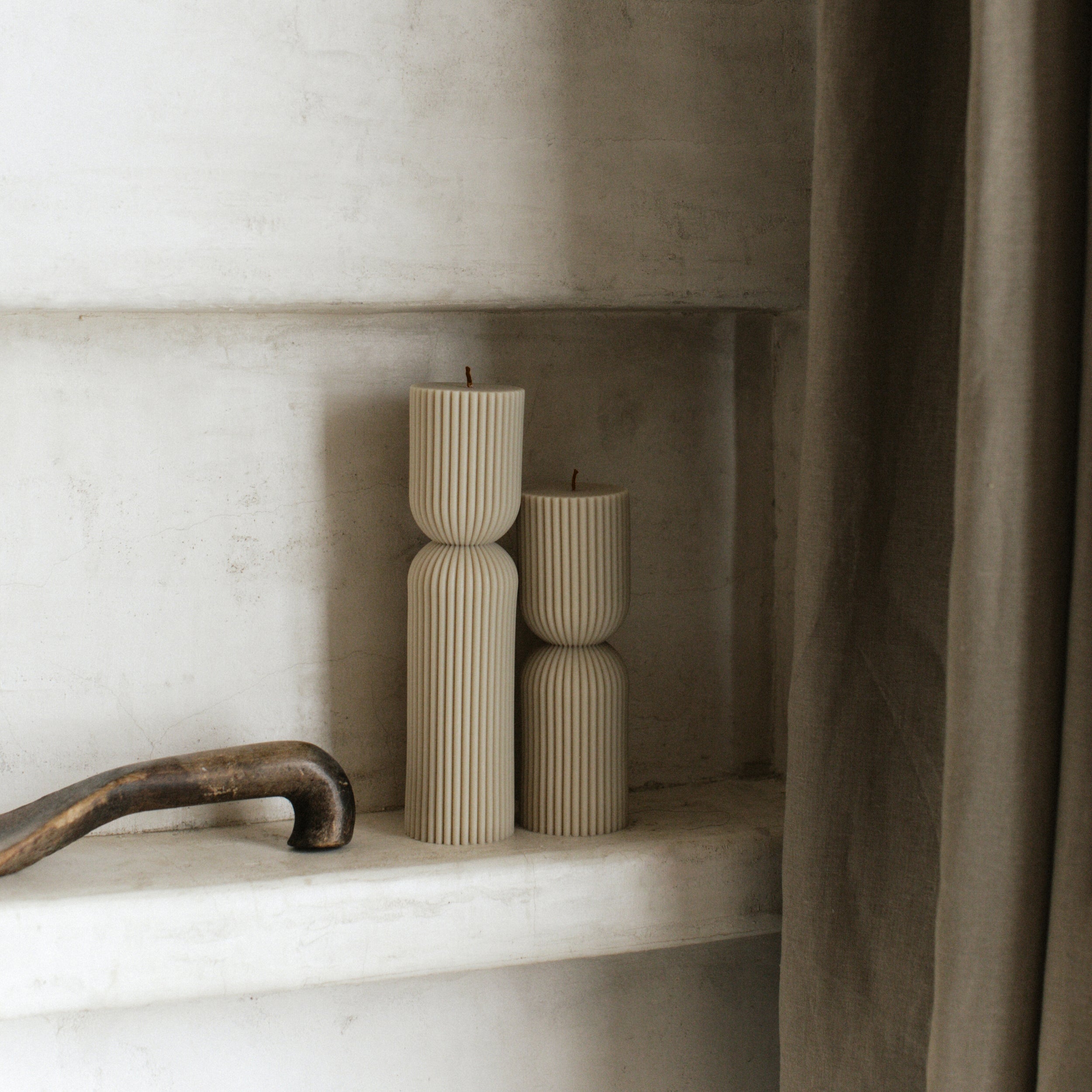 Hourglass set of two pillar candles on a marble shelf.