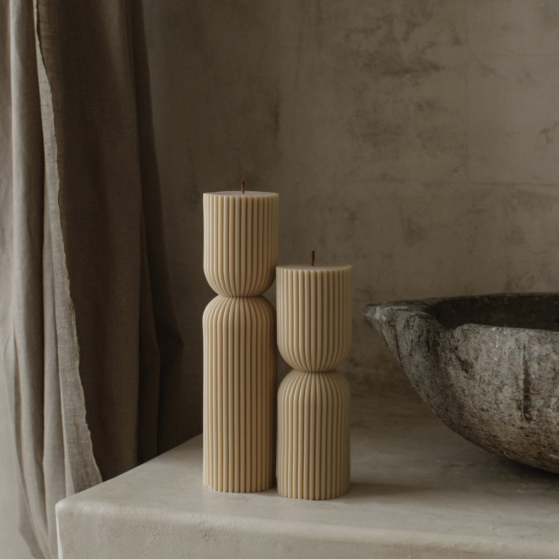 Close-up detail of handmade hourglass sculptural candle showing smooth soy wax texture and cotton wick