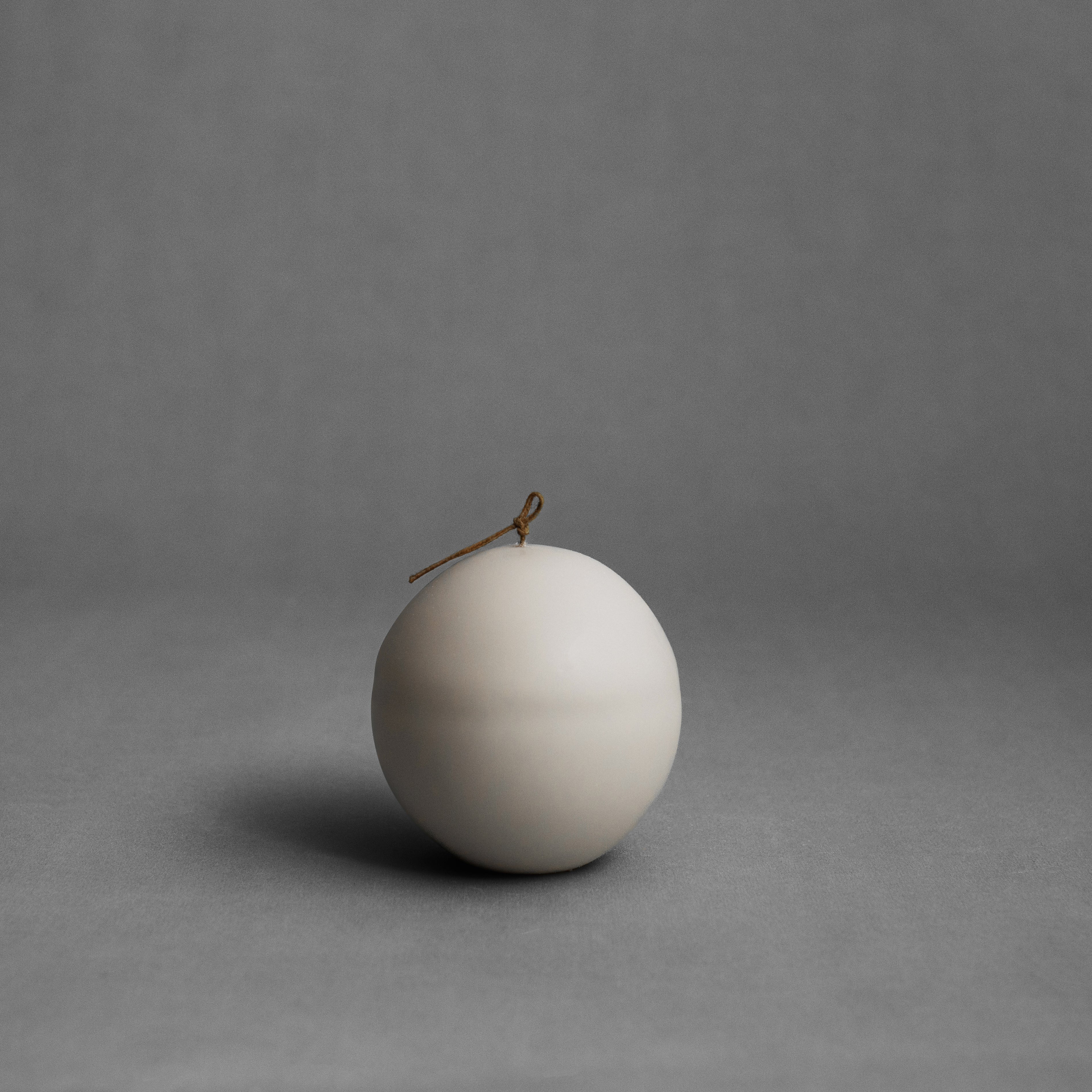 Light beige imperfect sphere soy wax pillar candle by LAWA featuring organic textured surface and sculptural design