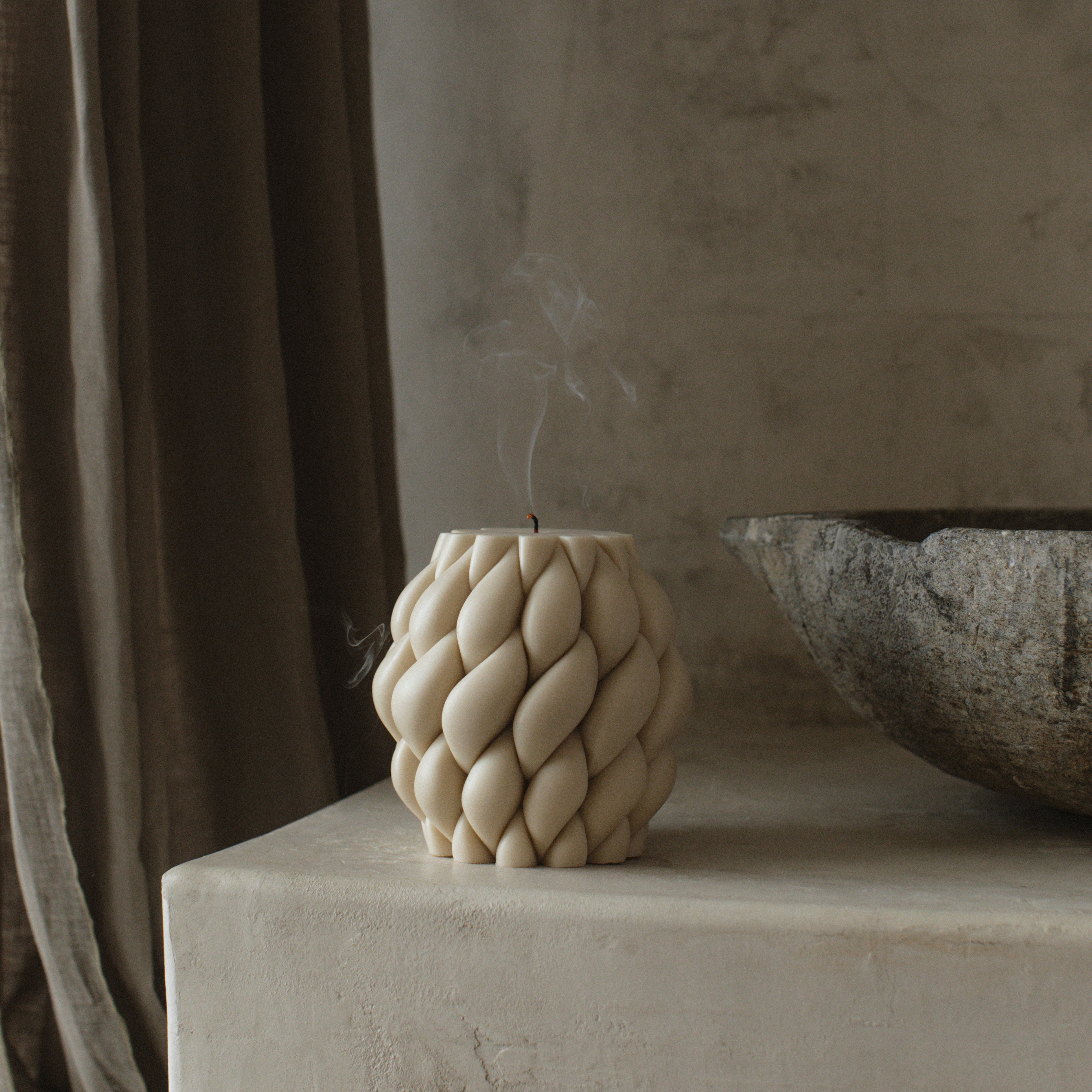 Decorative moon gray knot ball pillar candle on a surface with a neutral background