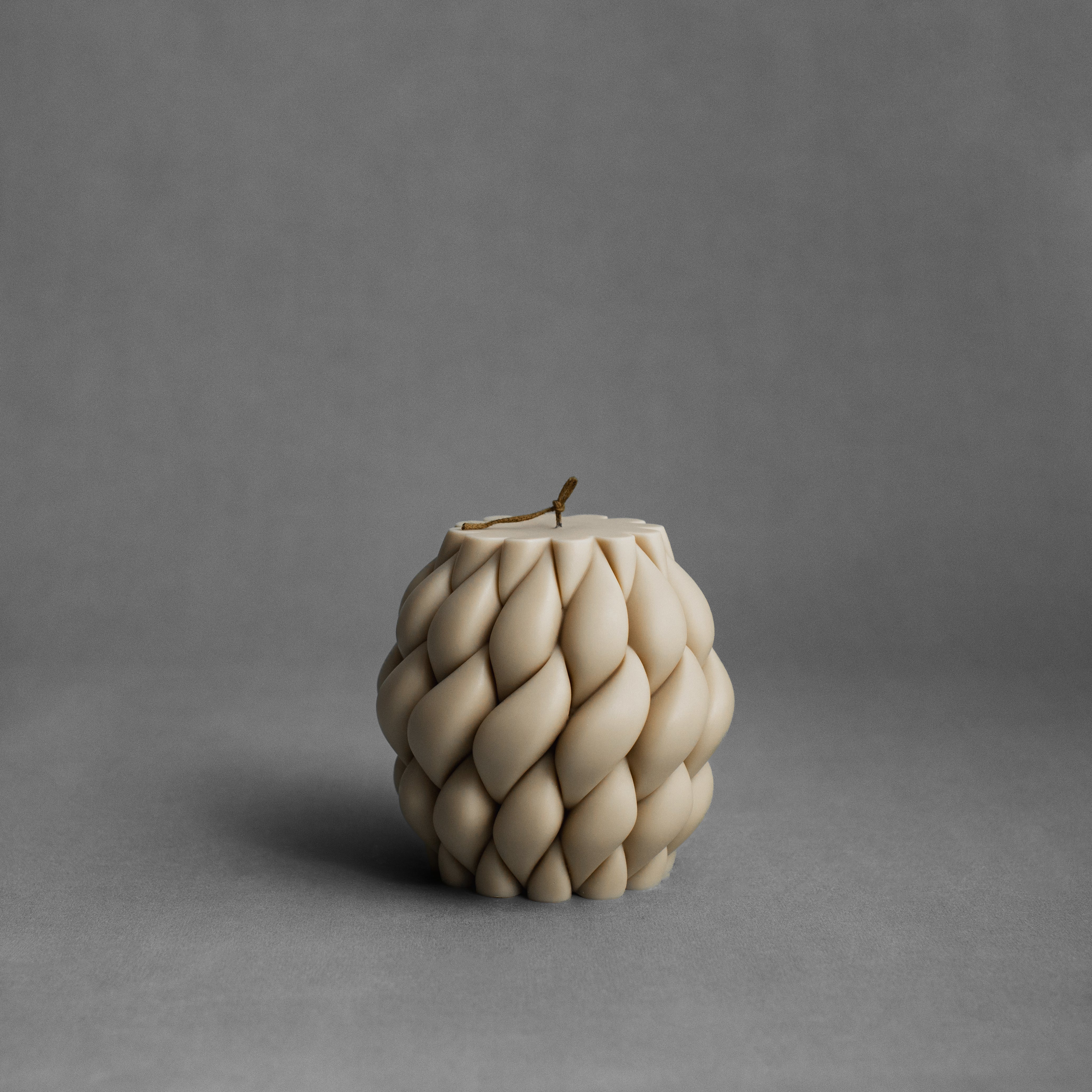 Sandstone knot ball candle by LAWA in a soft neutral tone with twisted sculptural design