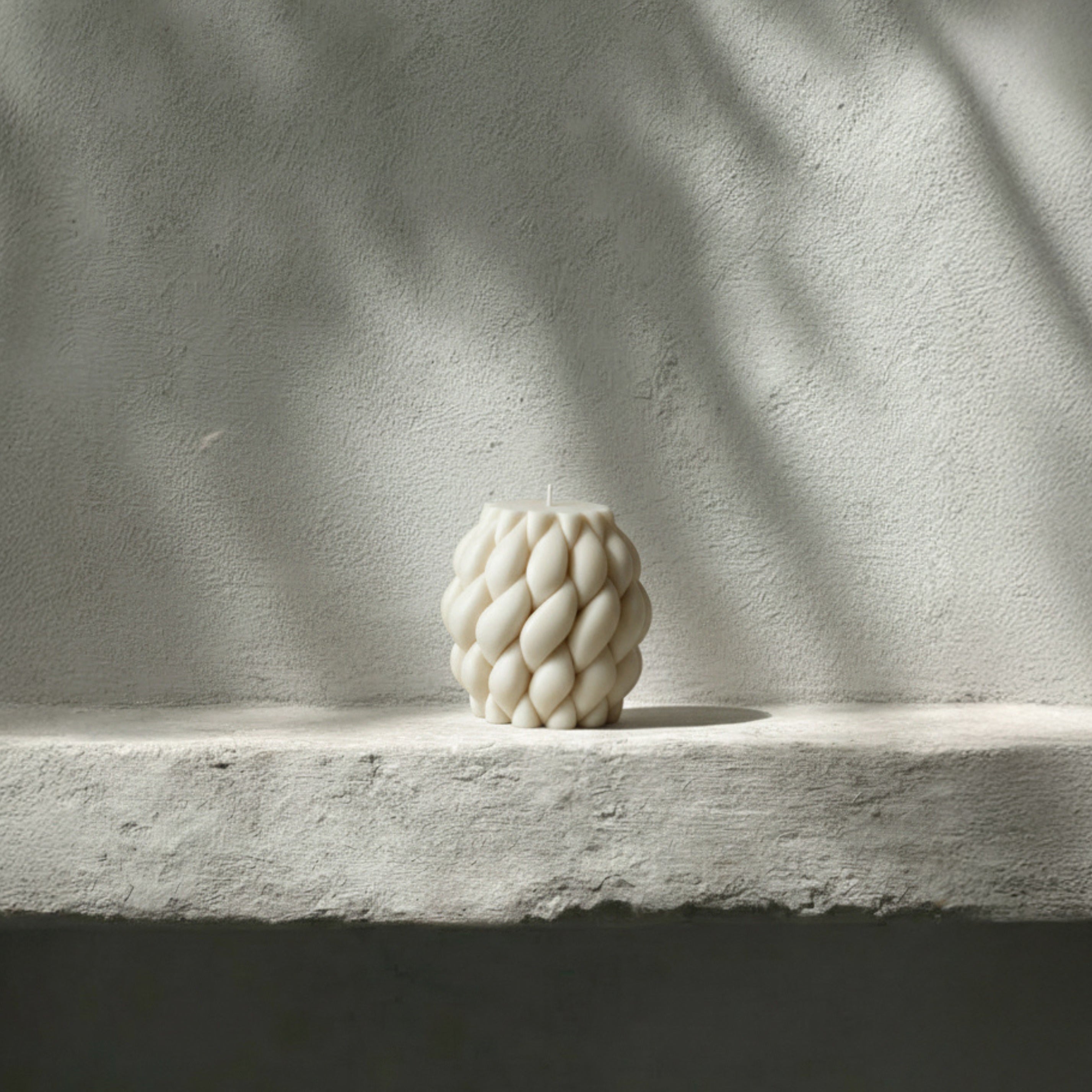 White knot ball pillar candle on a light stone surface