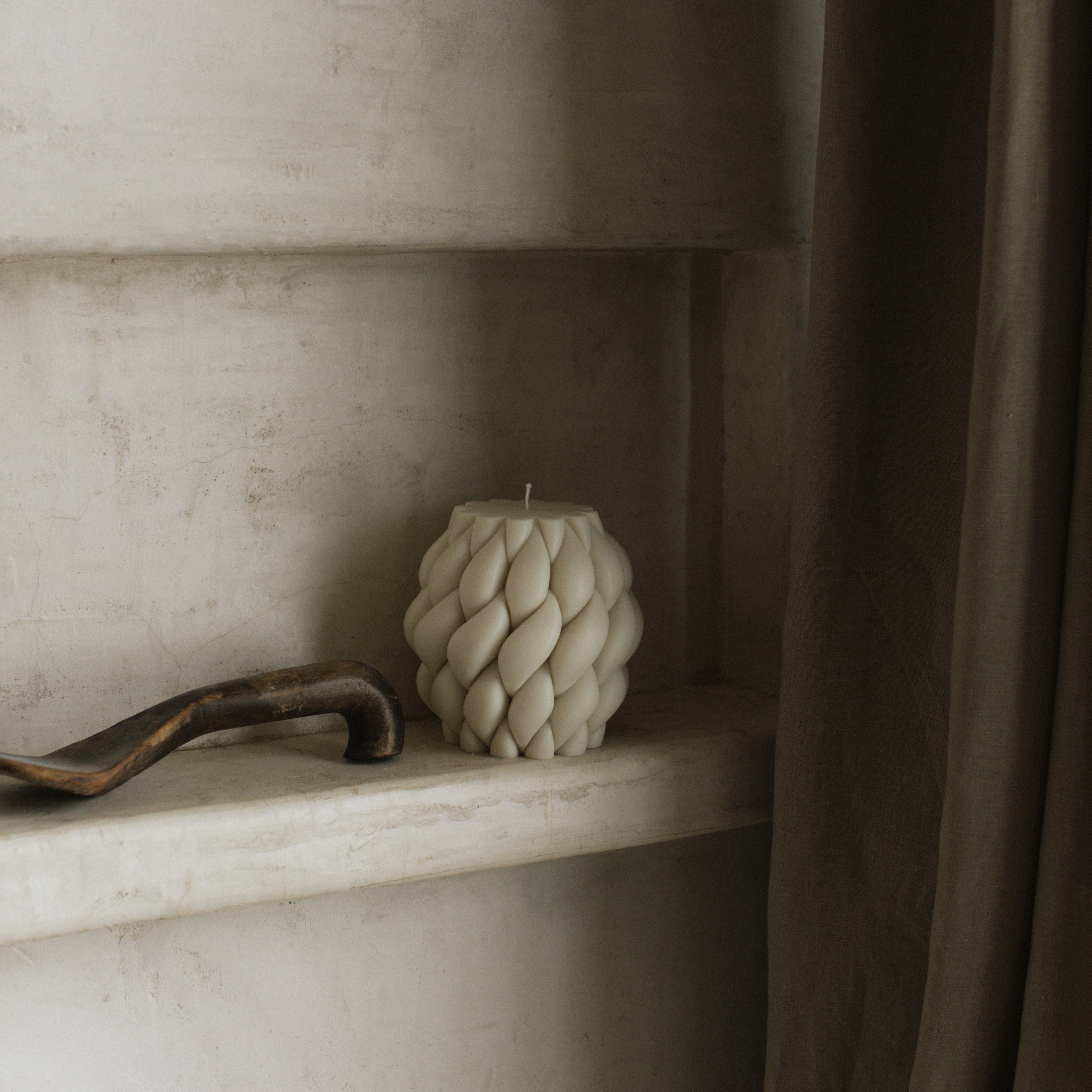 White Knot ball pillar candle on a shelf with a neutral background