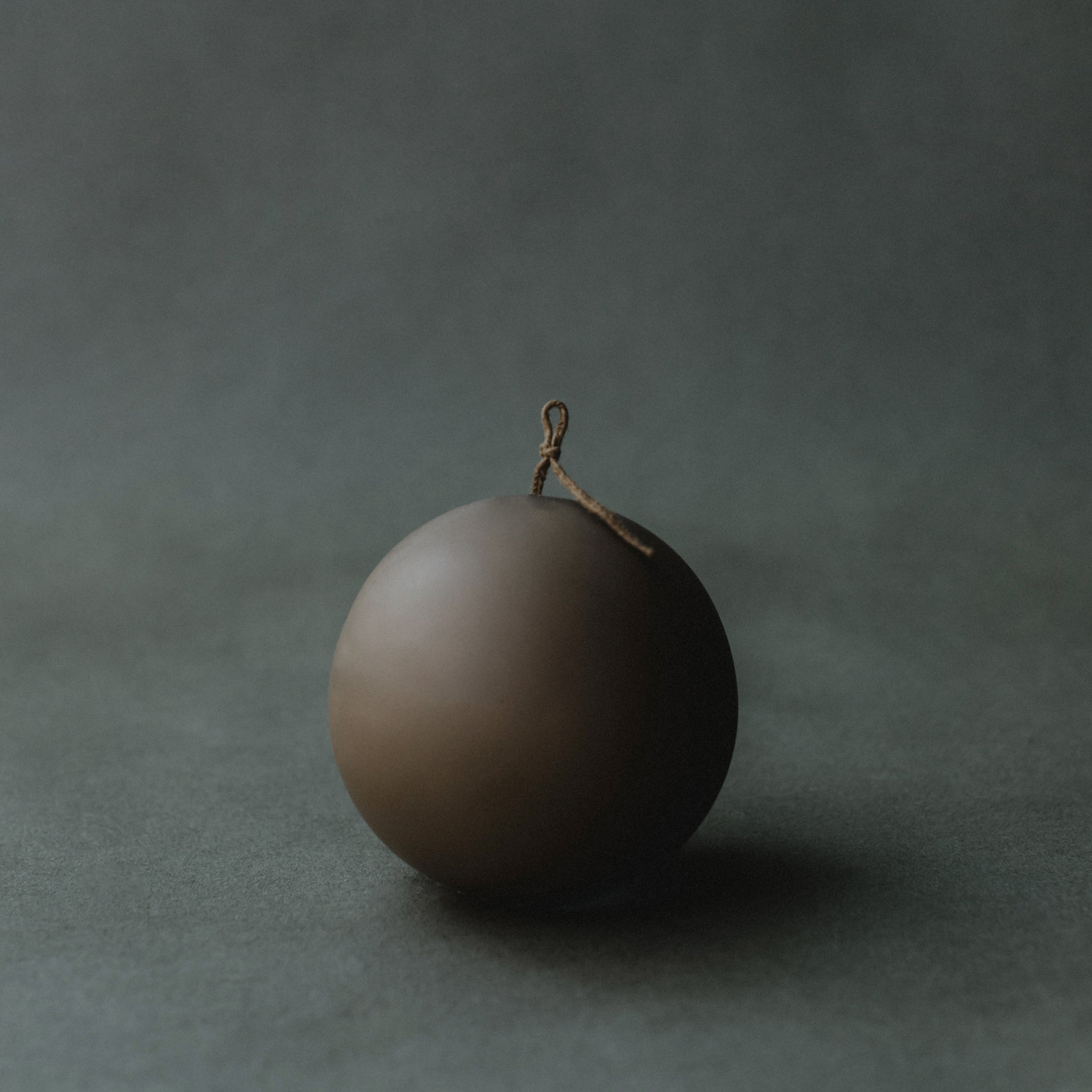 Kobicha brown sphere candle on a dark gray background