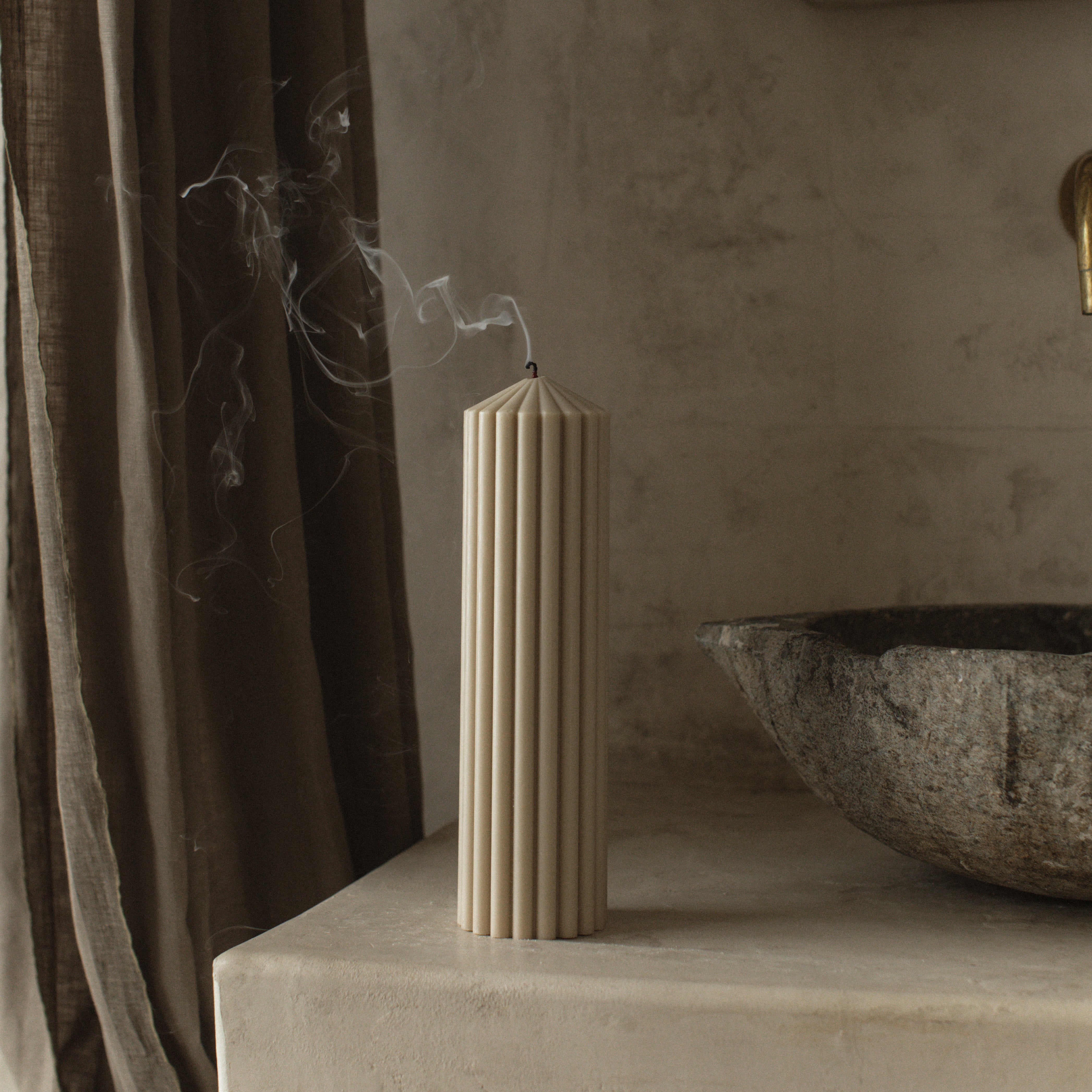 Moon gray large peak candle by LAWA designed with a clean minimalist mountain silhouette on a stone surface next to a stone sink.