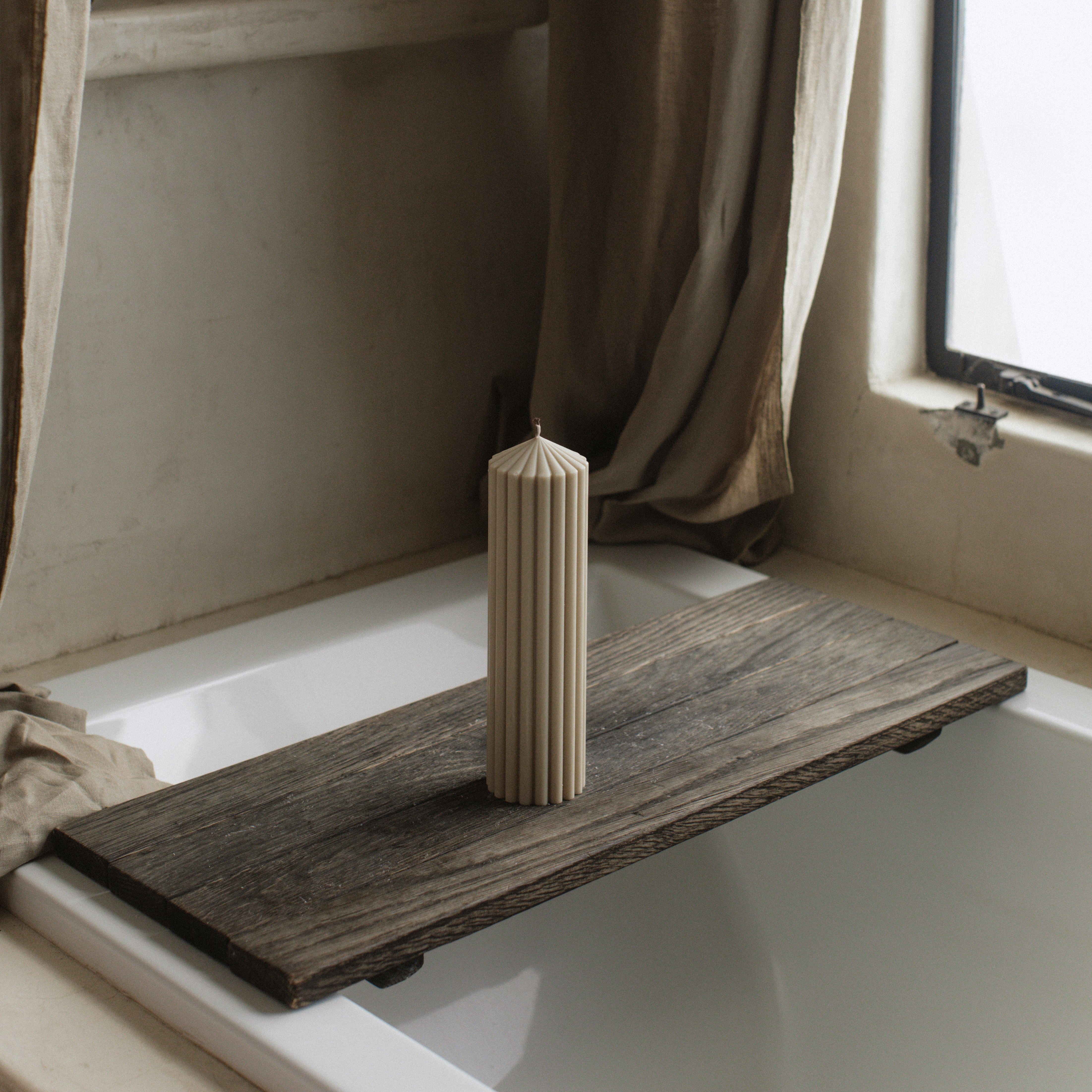 LAWA large moon gray soy wax peak candle featuring sculptural modern geometry on a Wooden shelf and  windowsill next to a curtain