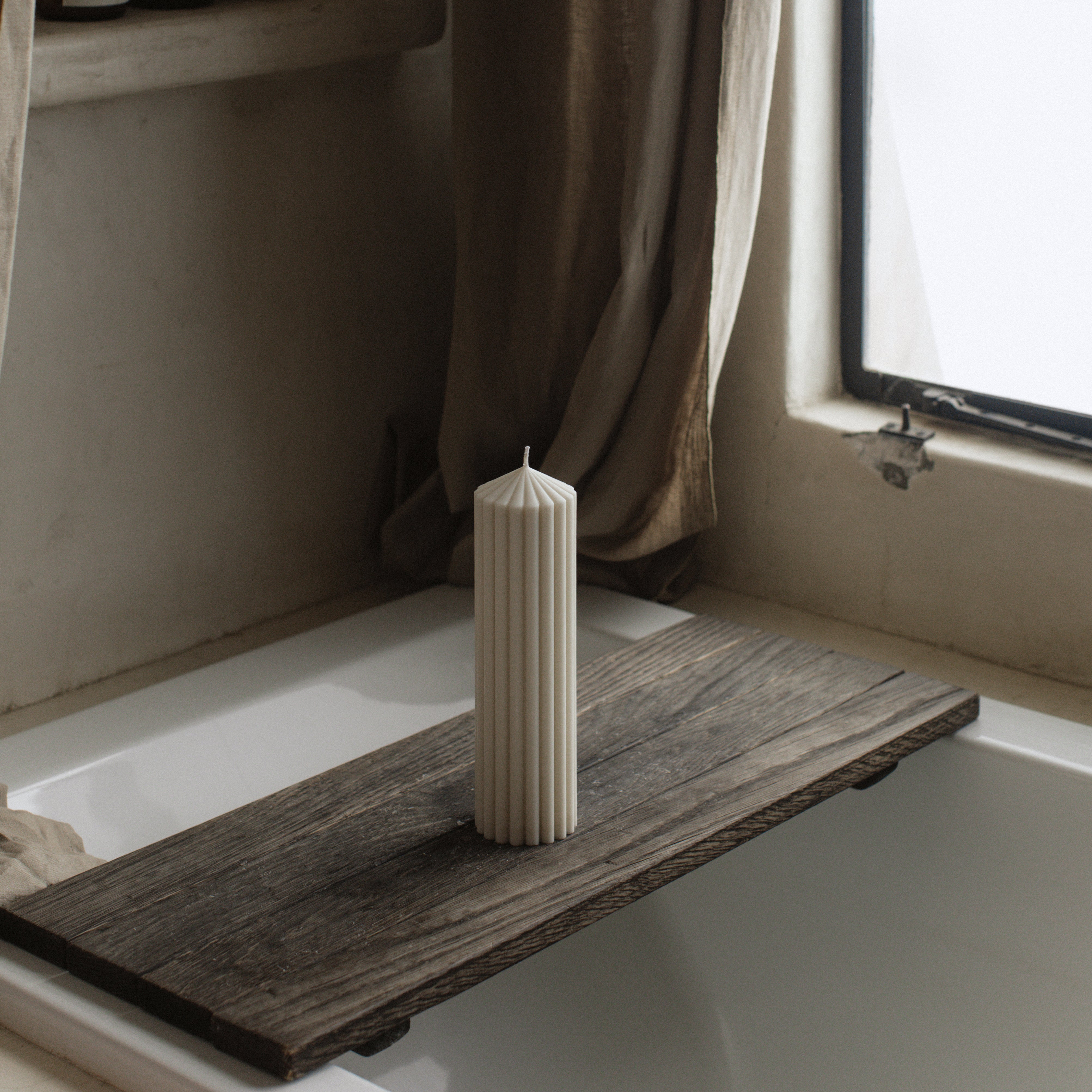 LAWA large white soy wax peak candle featuring striking geometric height on a wooden shelf by a window with curtains
