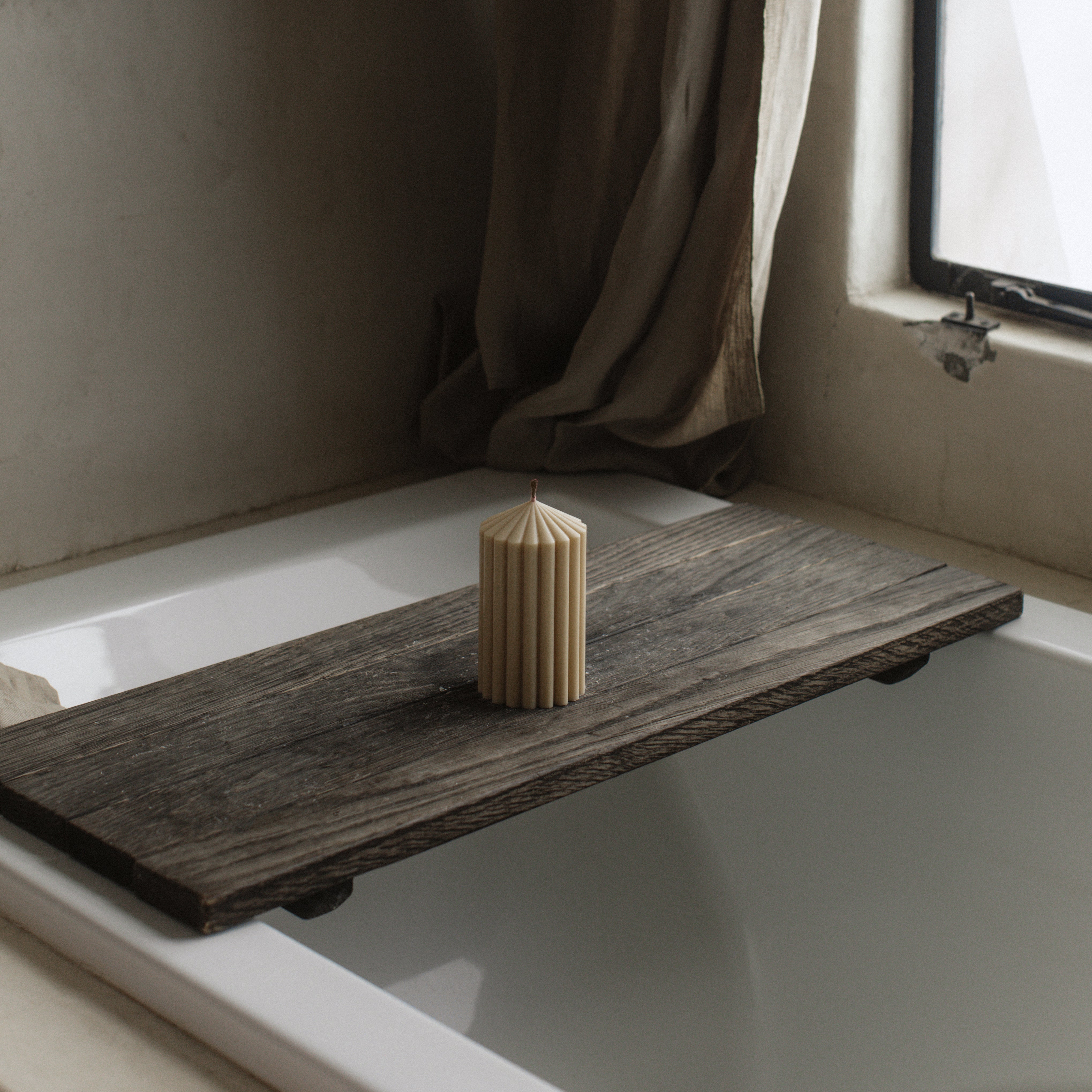 LAWA small sandstone soy wax peak candle in a warm neutral tone with geometric design on a wooden bathtub tray in the bathroom