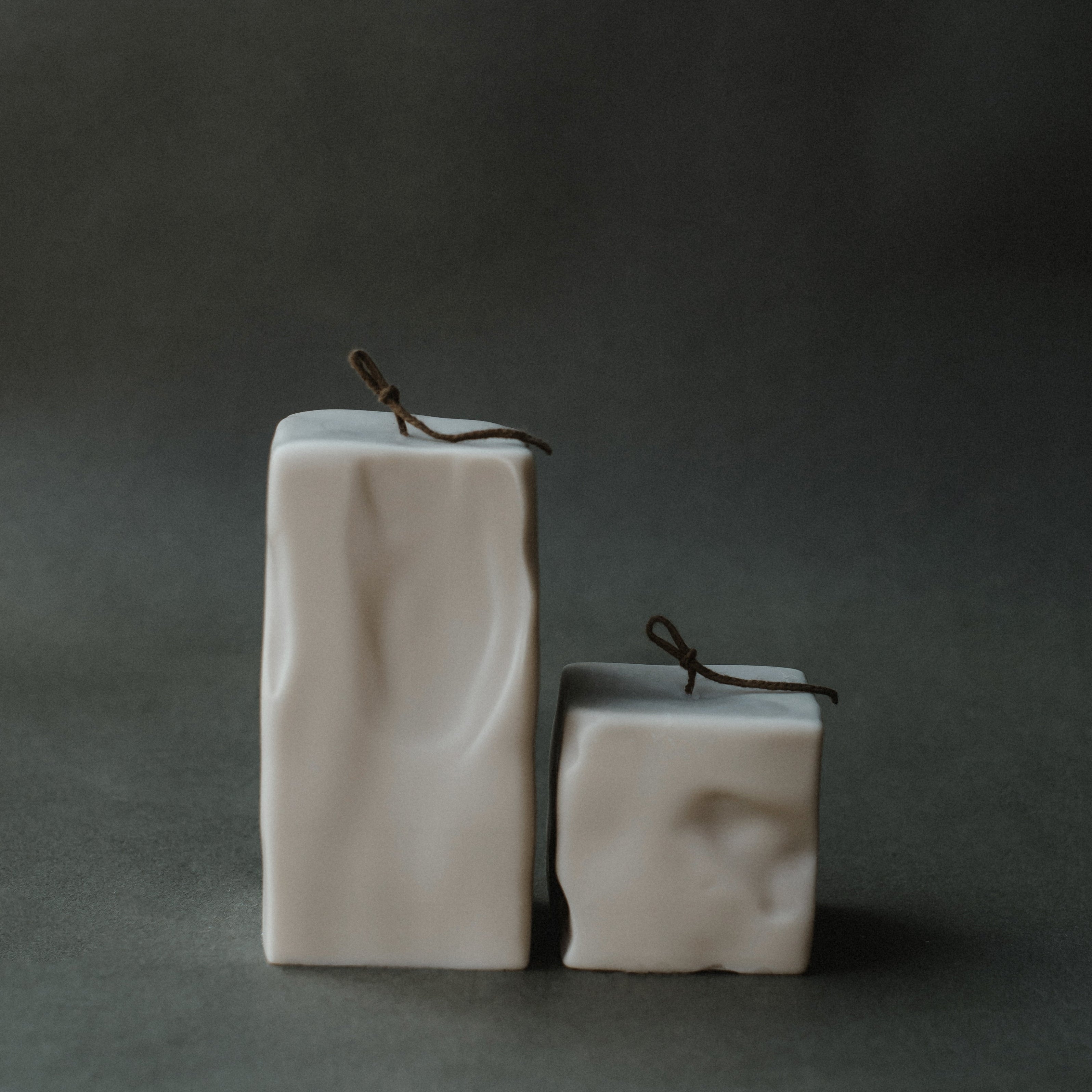 Set of Raw block candles with textured surface on a dark green background