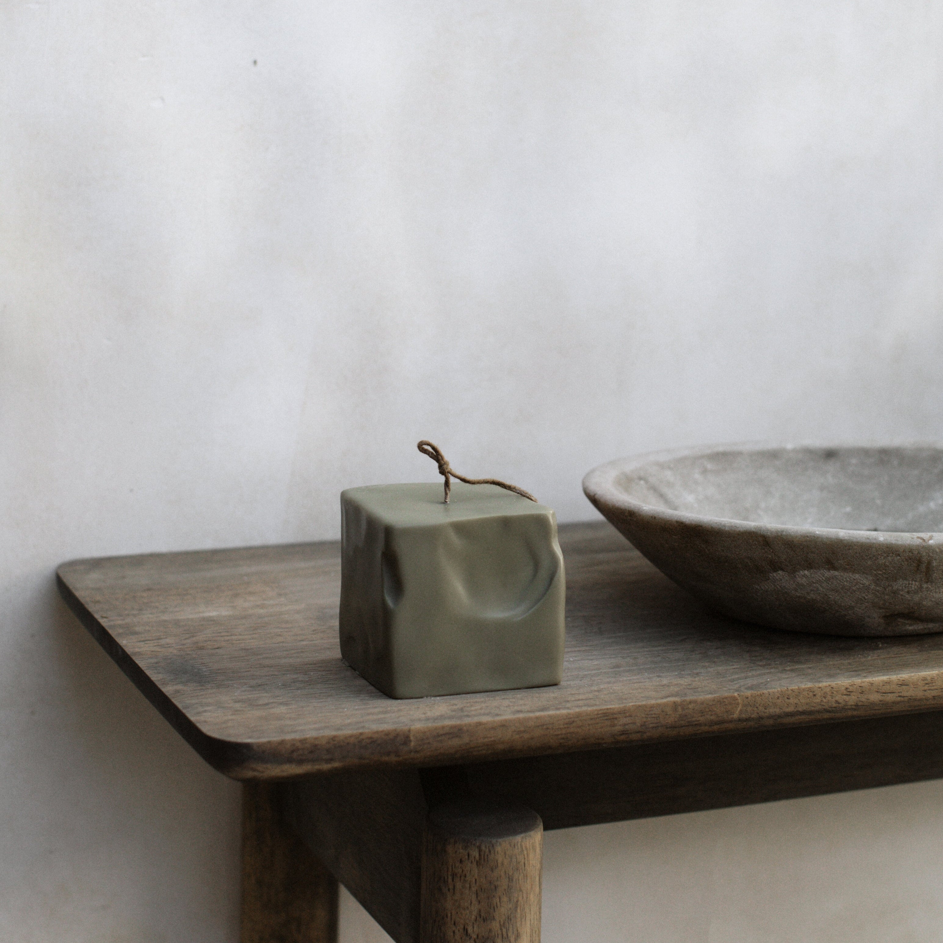 Minimal small earthy green soy wax raw block candle by LAWA on a wooden table with a plain background