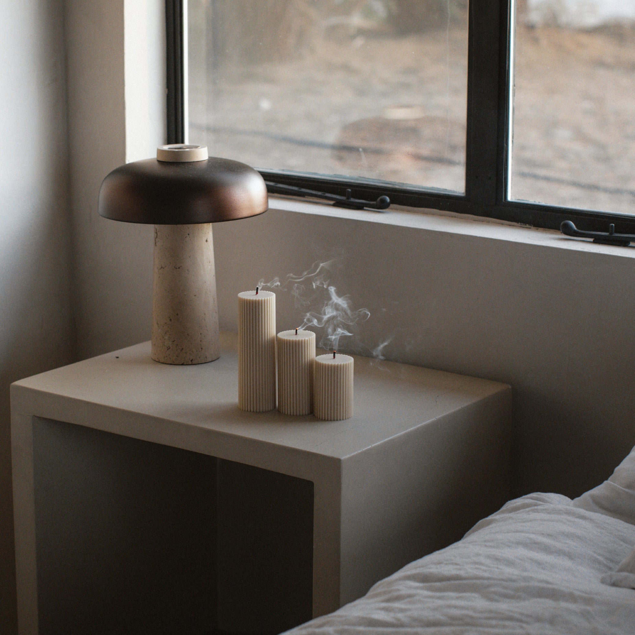 Three pillar ribbed candles in a set on the nightstand