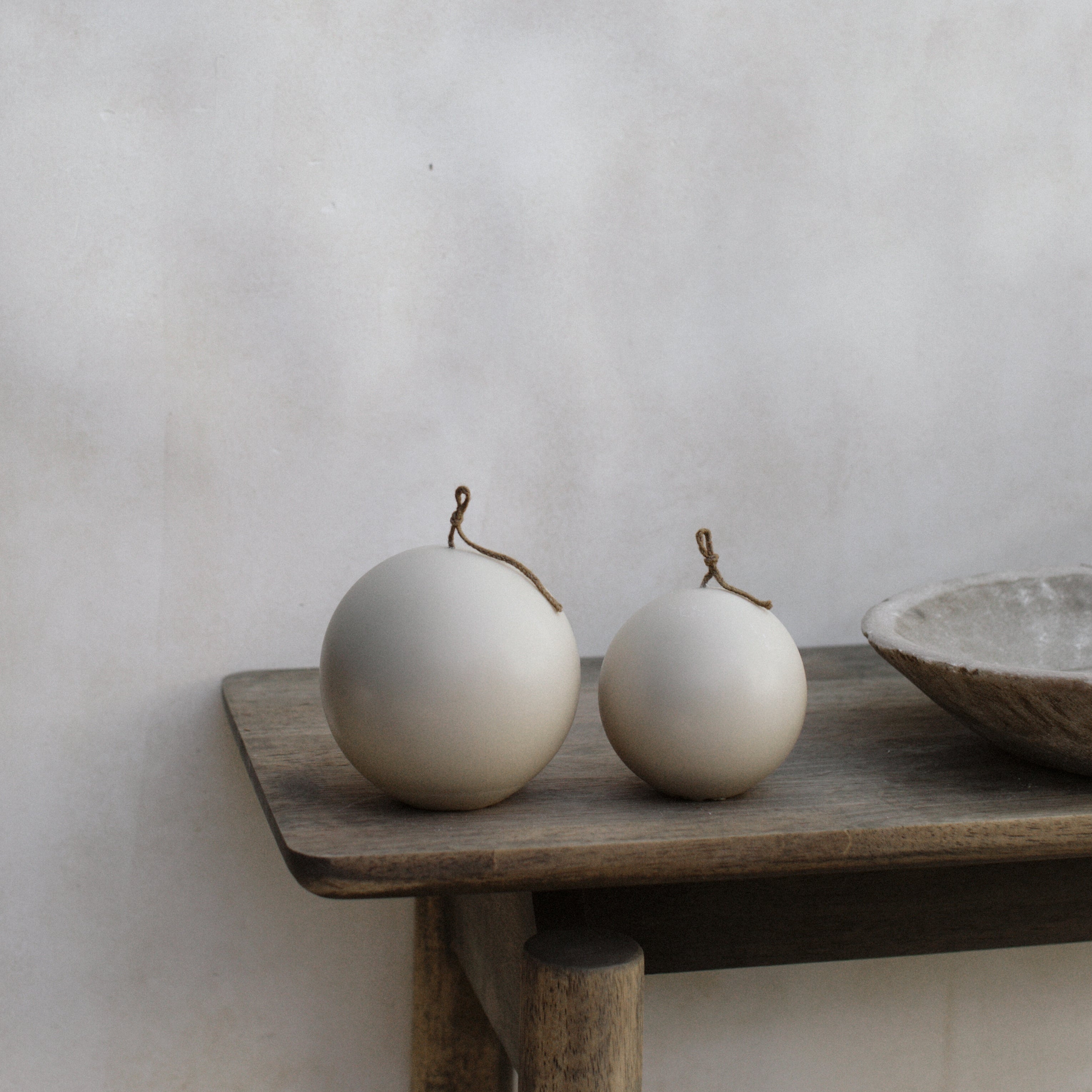 Sphere set of two pillar candles on a wooden surface with a neutral background