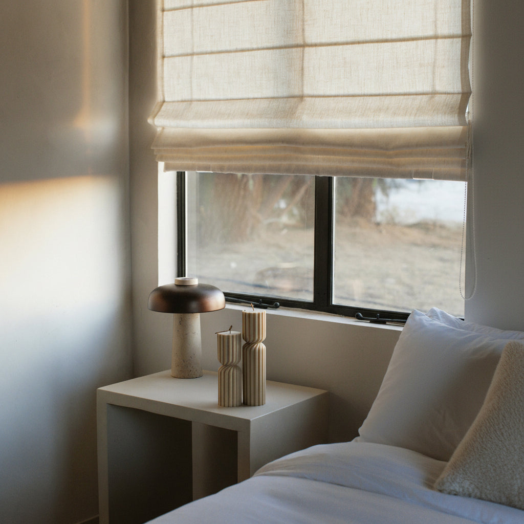 Spiral set of two pillar candles in a bedroom with a window, nightstand, and decorative items.