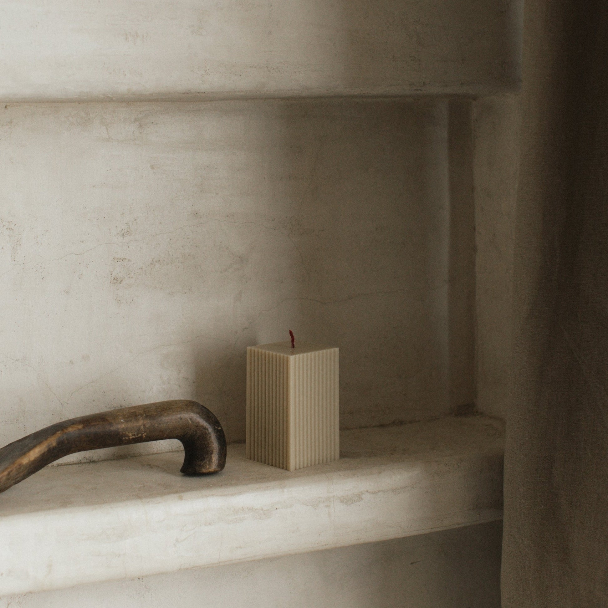 Gray ribbed square candle by LAWA featuring minimalist vertical grooves on a marble shelf in the bathroom and shower