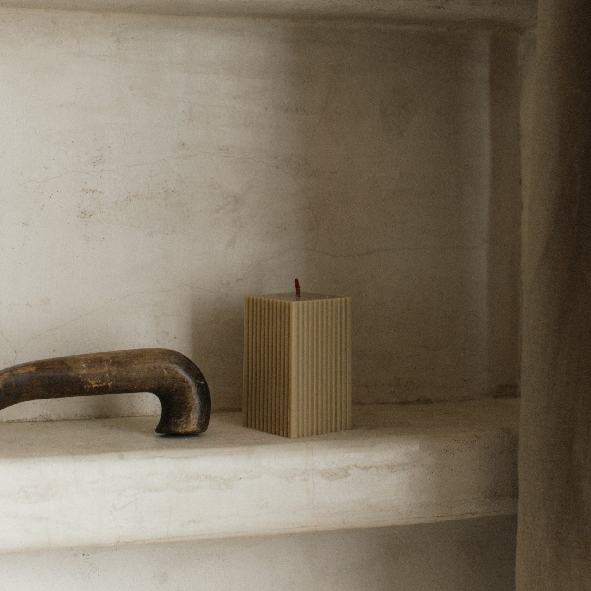 Earthy olive beige ribbed square candle by LAWA, modern geometric soy wax design on a shelf with a textured background