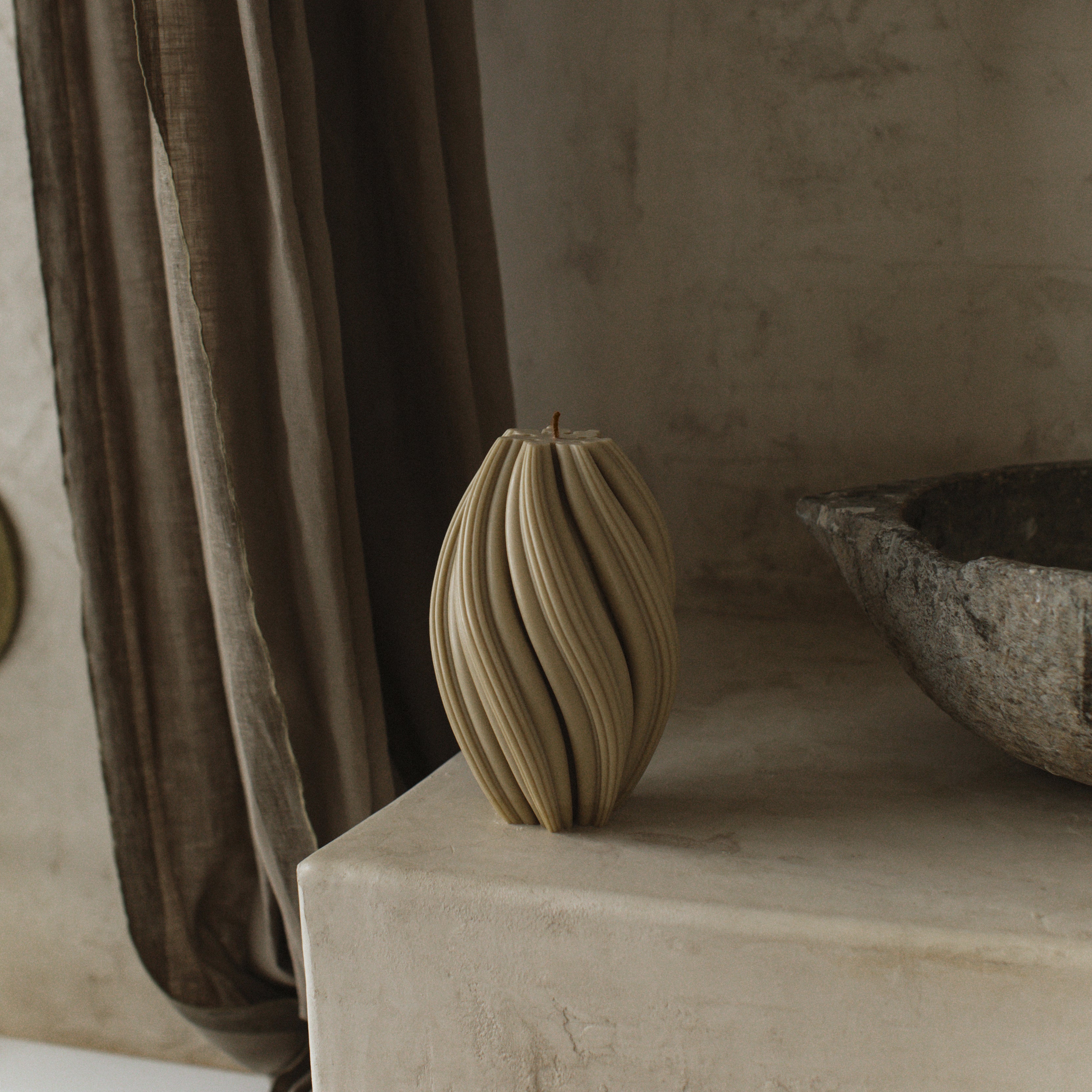Earthy olive beige large swirl pillar candle by LAWA with elegant spiral detailing on a stone surface with a neutral background