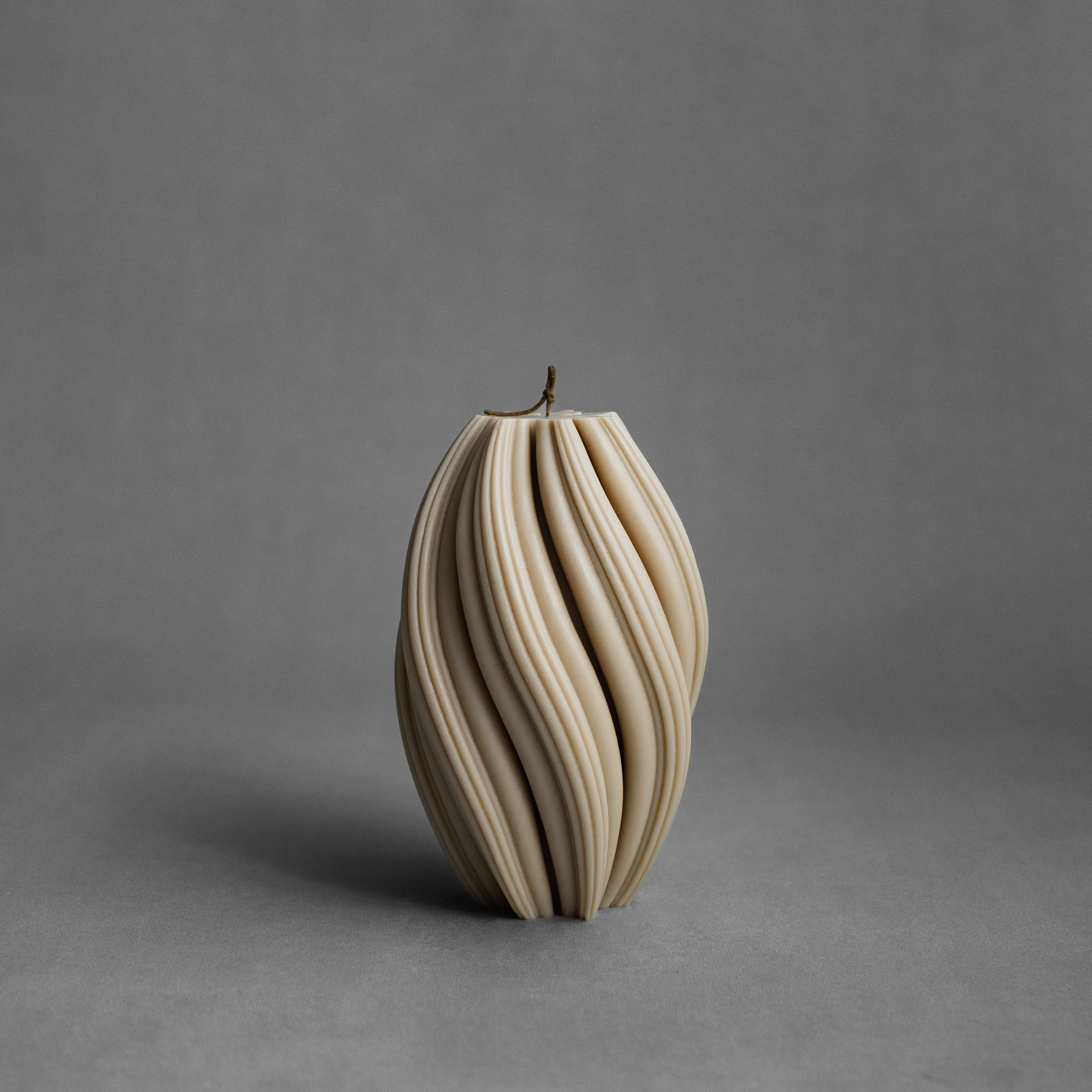Large sandstone swirl pillar candle by LAWA with bold spiraling sculptural pattern