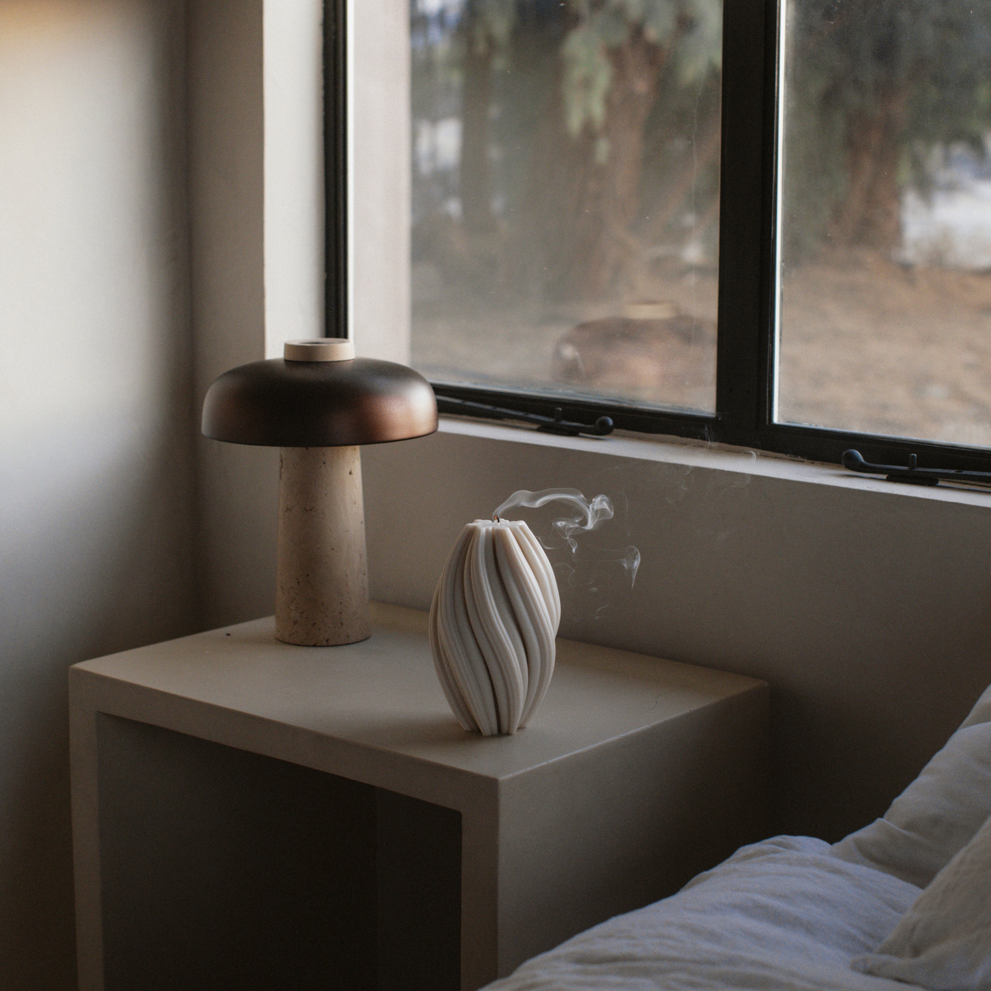 LAWA large white swirl candle featuring tall twisted spiral texture on a nightstand next to a window
