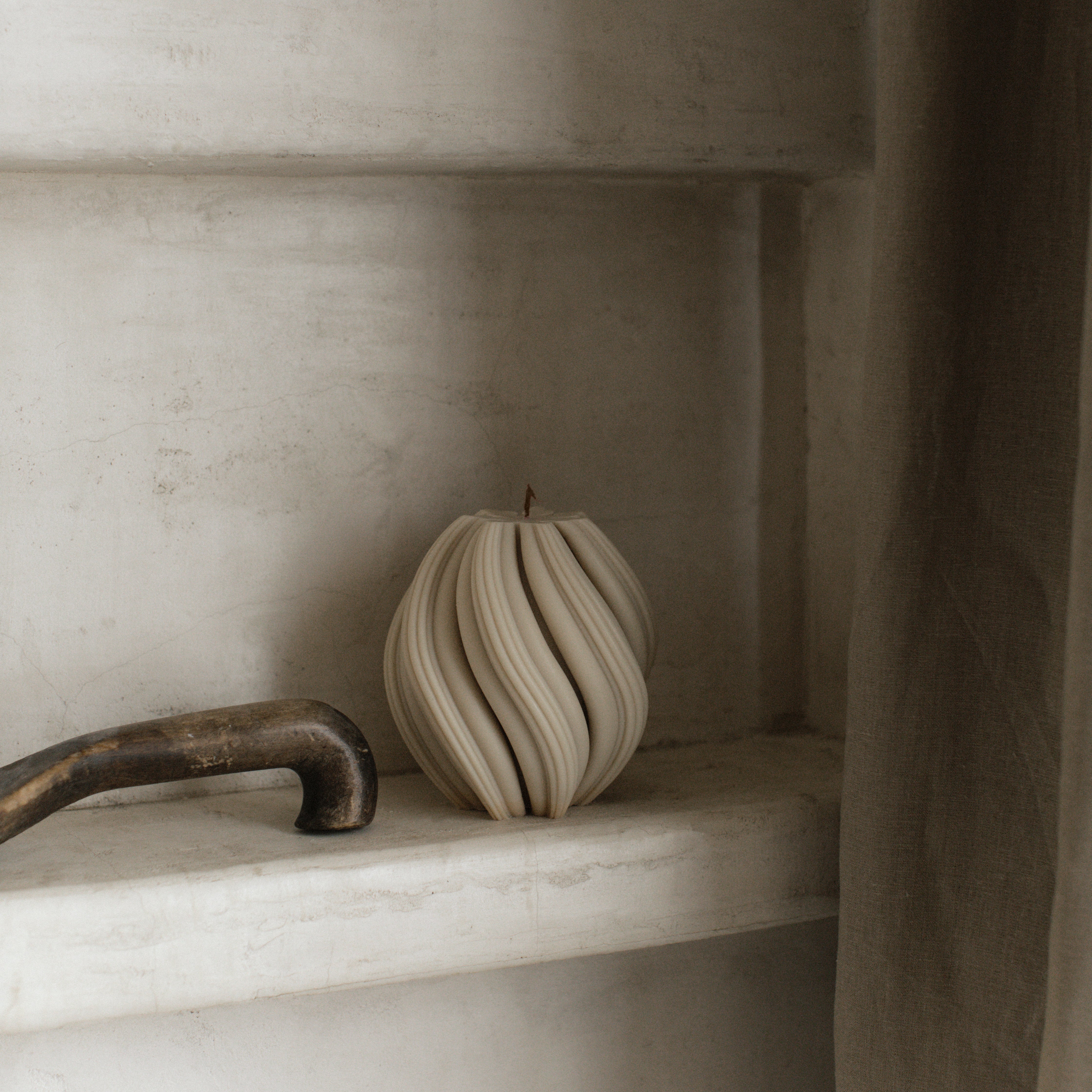 Moon gray medium swirl candle by LAWA with modern spiraling design on a marble shelf with a neutral background