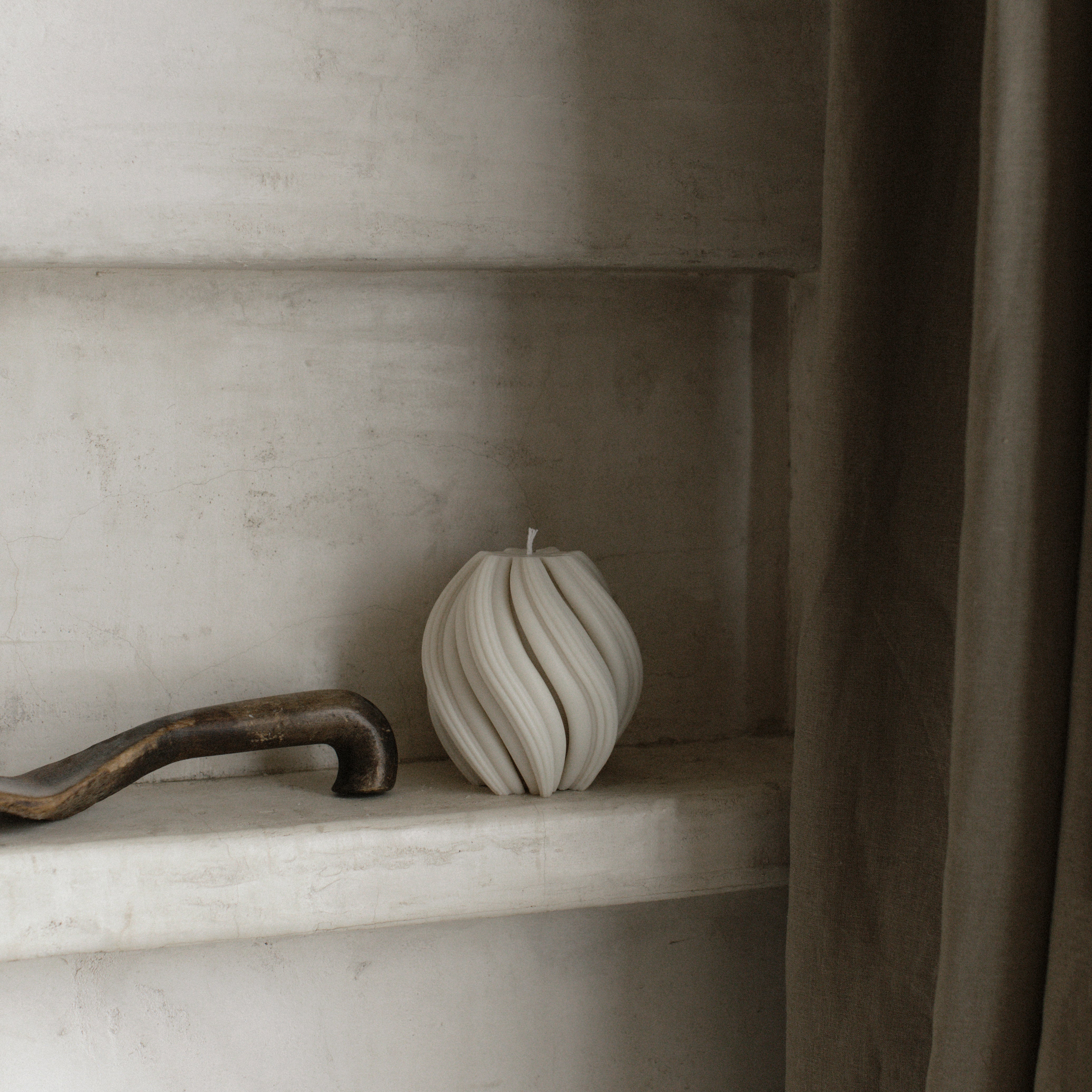 White medium swirl pillar candle by LAWA with smooth twisted silhouette on a shelf with a neutral background