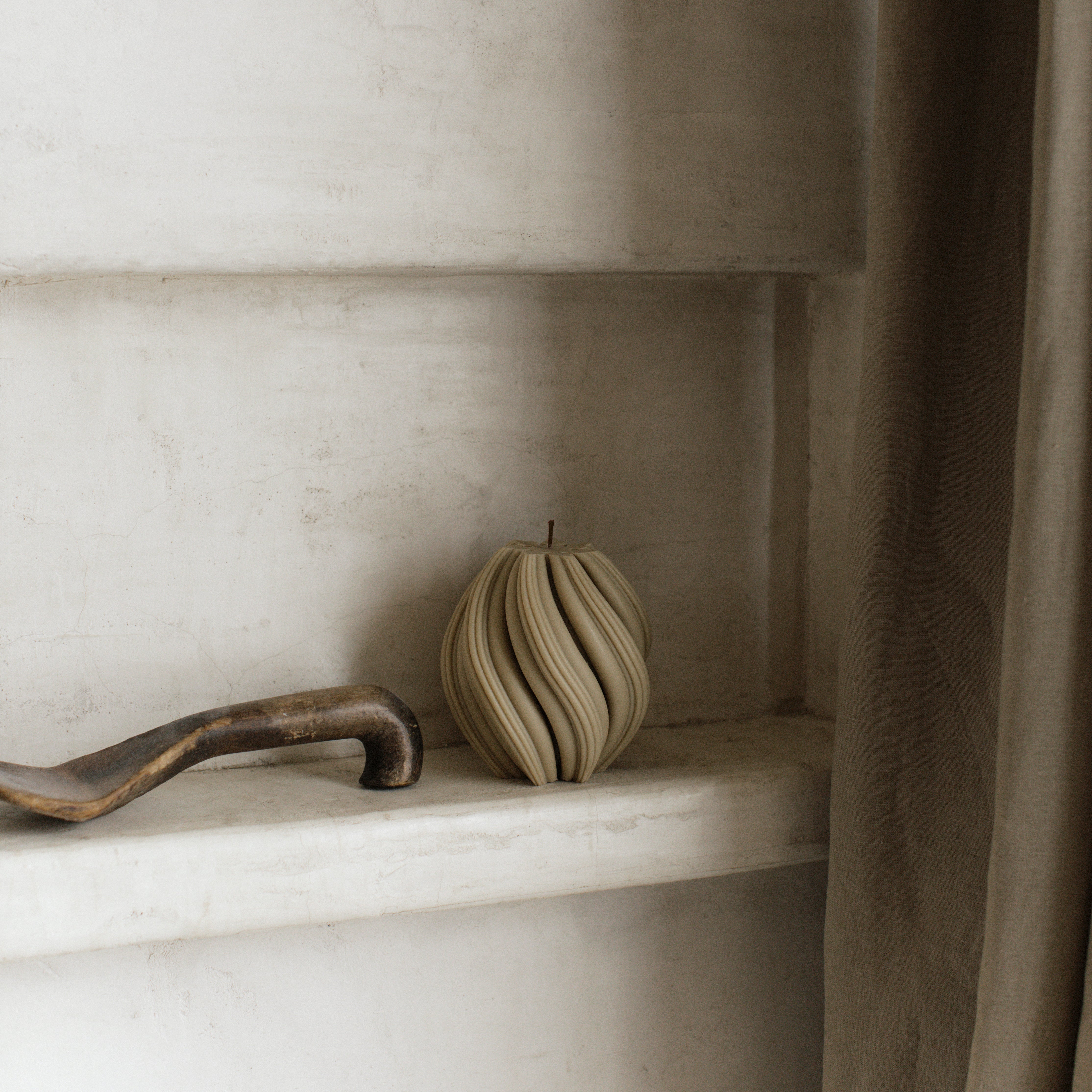 LAWA small swirl candle in olive beige featuring curved spiral texture on a shelf with a neutral background