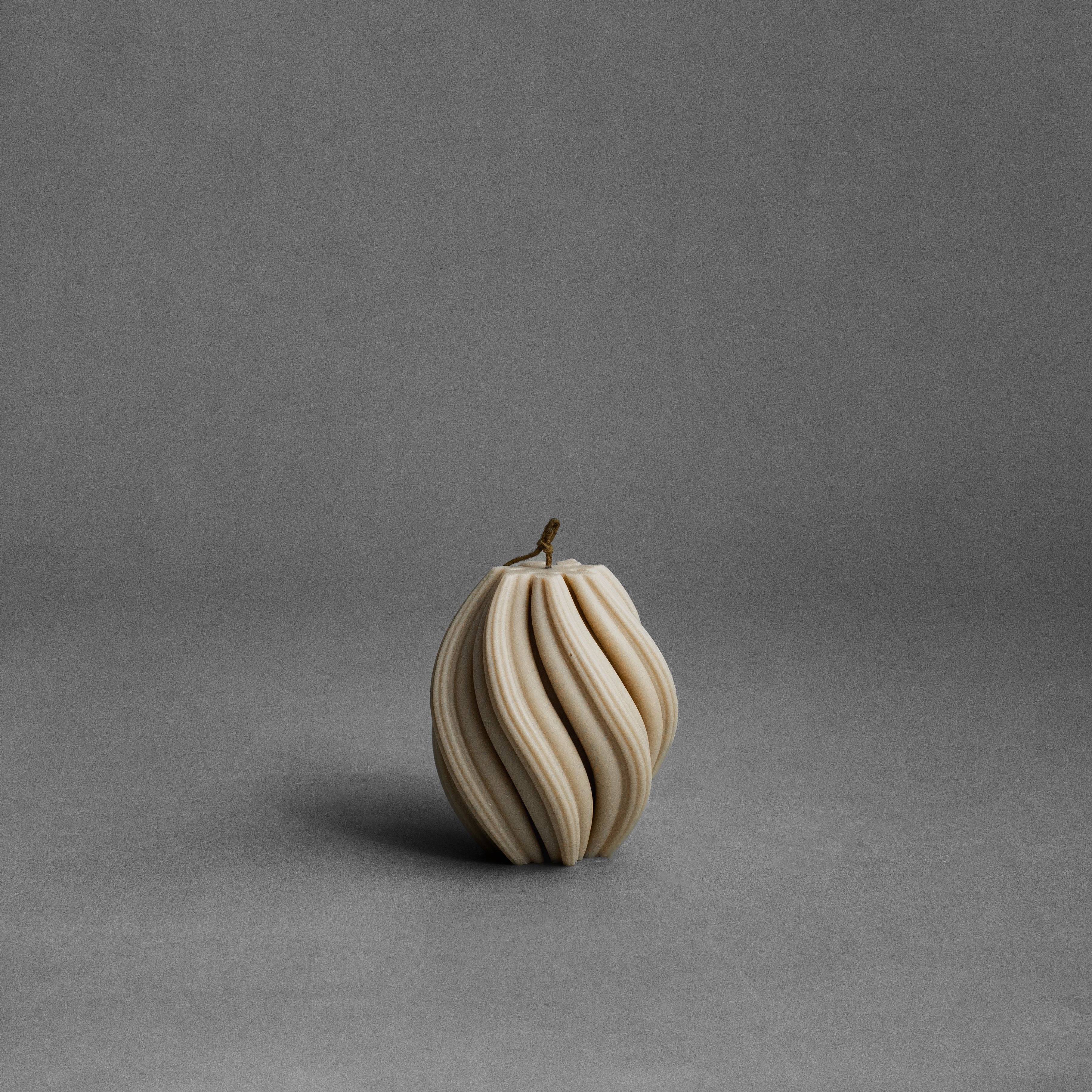Small sandstone swirl pillar candle by LAWA with soft spiral sculptural detailing