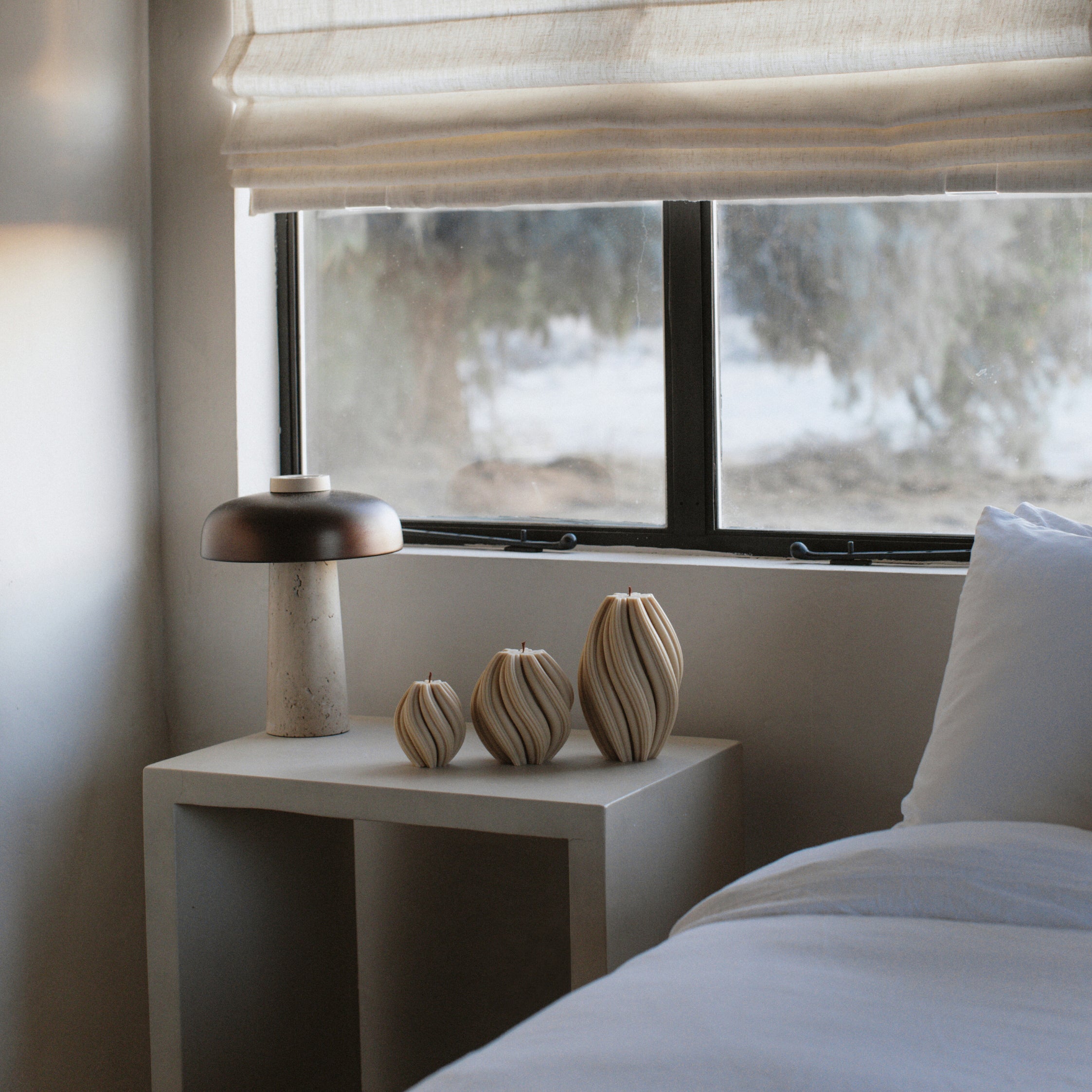 LAWA sandstone swirl candle trio featuring elegant spiral sculptural textures in a softly lit room.