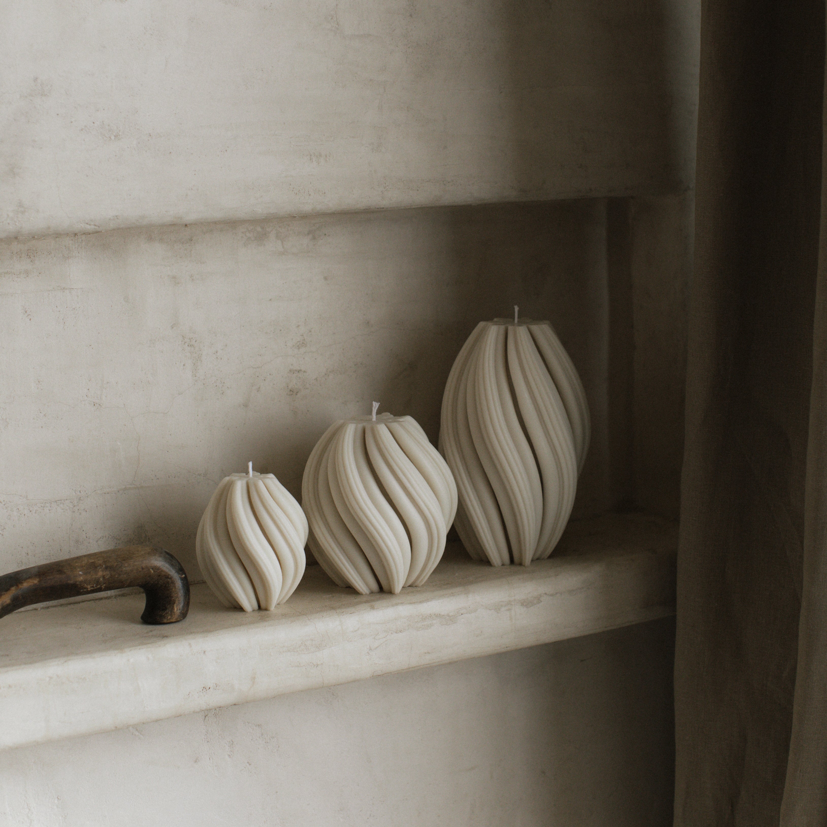 White soy wax swirl candle set of 3 by LAWA with modern twisted spiral silhouettes on a shelf against a neutral wall.