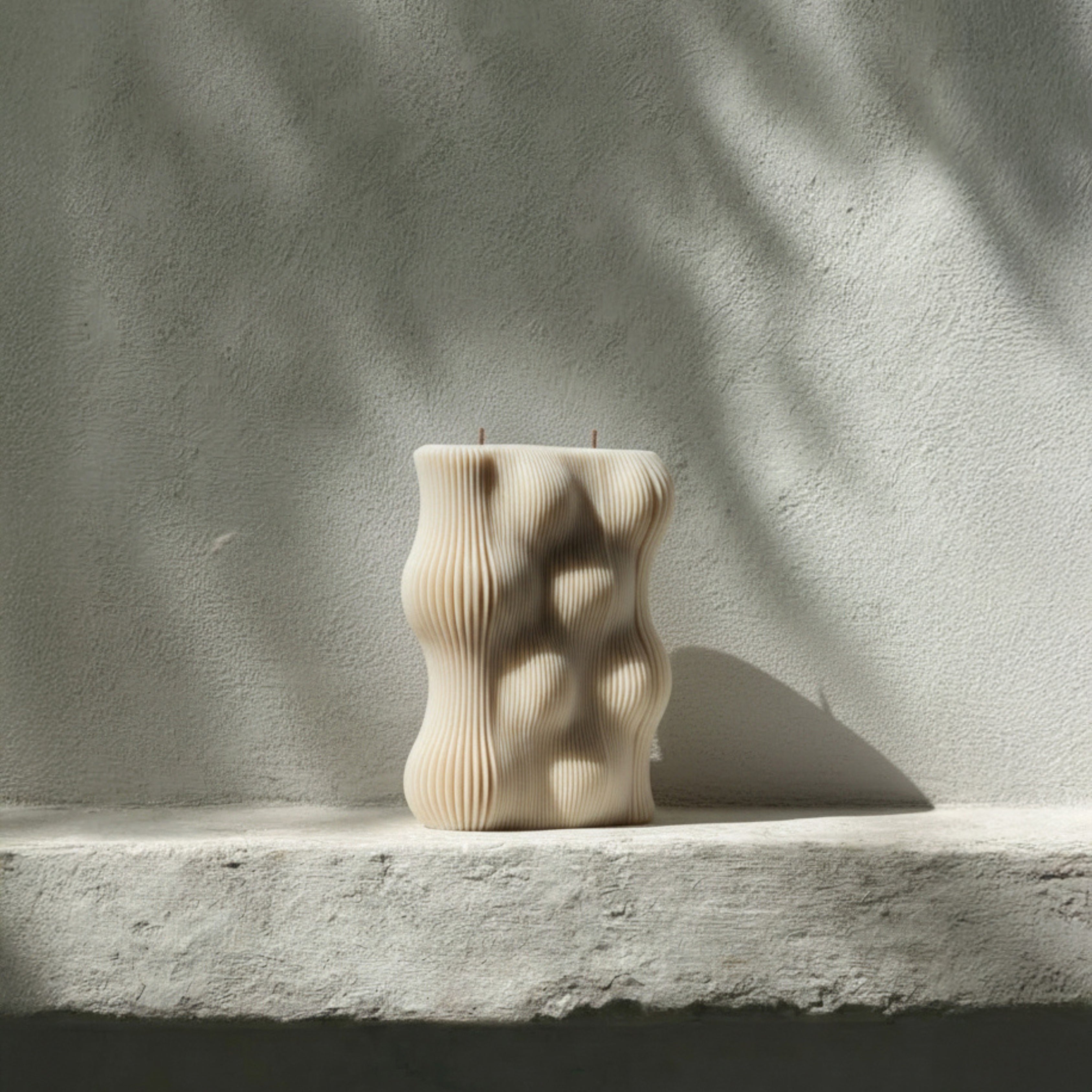 Wavy pillar ribbed candle on a stone surface with a neutral background