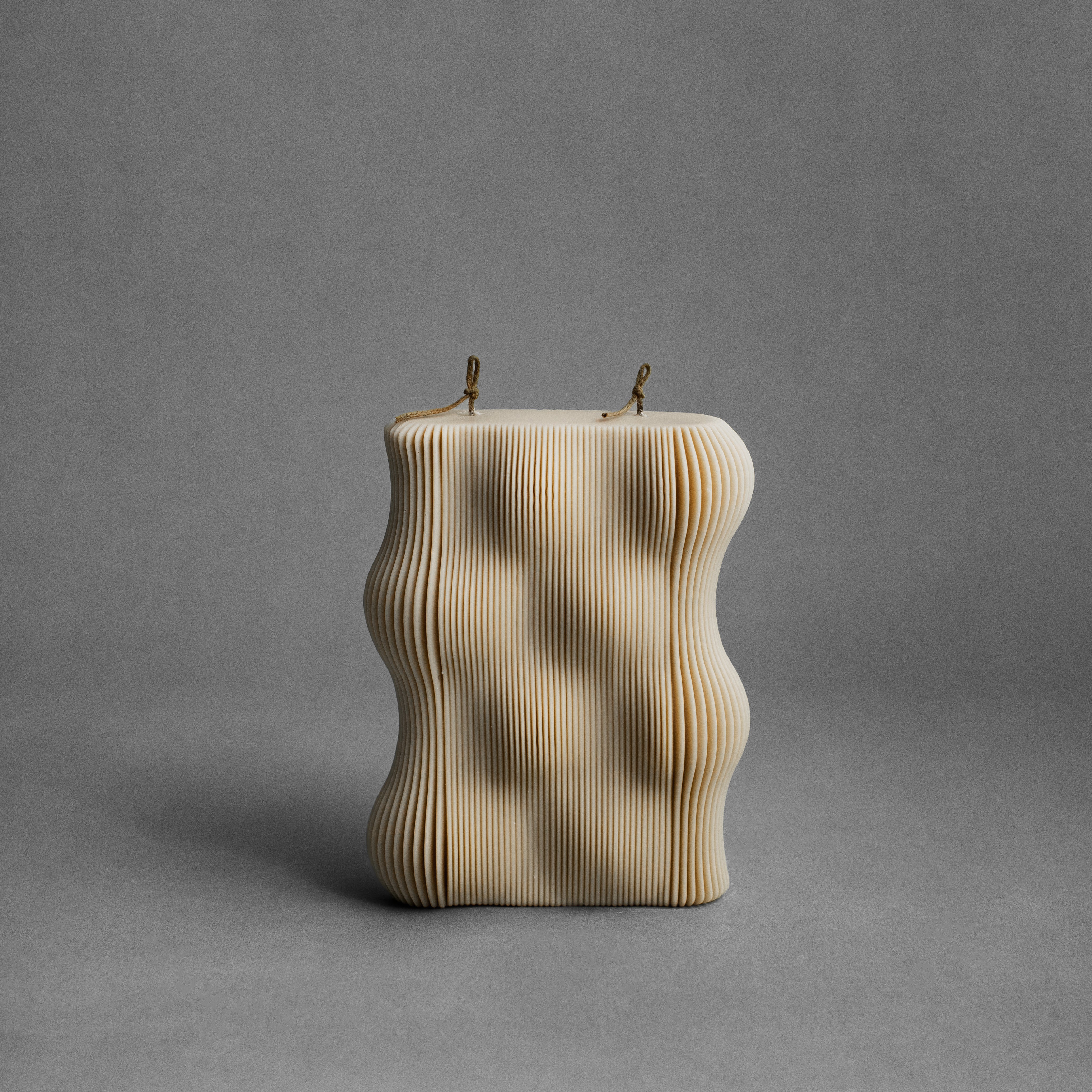 Sandstone wavy pillar candle by LAWA featuring soft neutral tone and curving texture